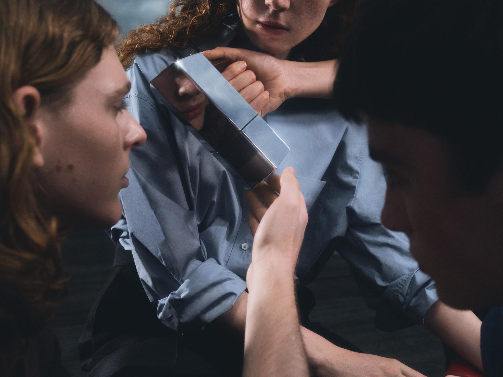 Drei Personen betrachten den reflektierenden Menhir Espressokocher von Alessi, ein Designobjekt für Kaffeeliebhaber.