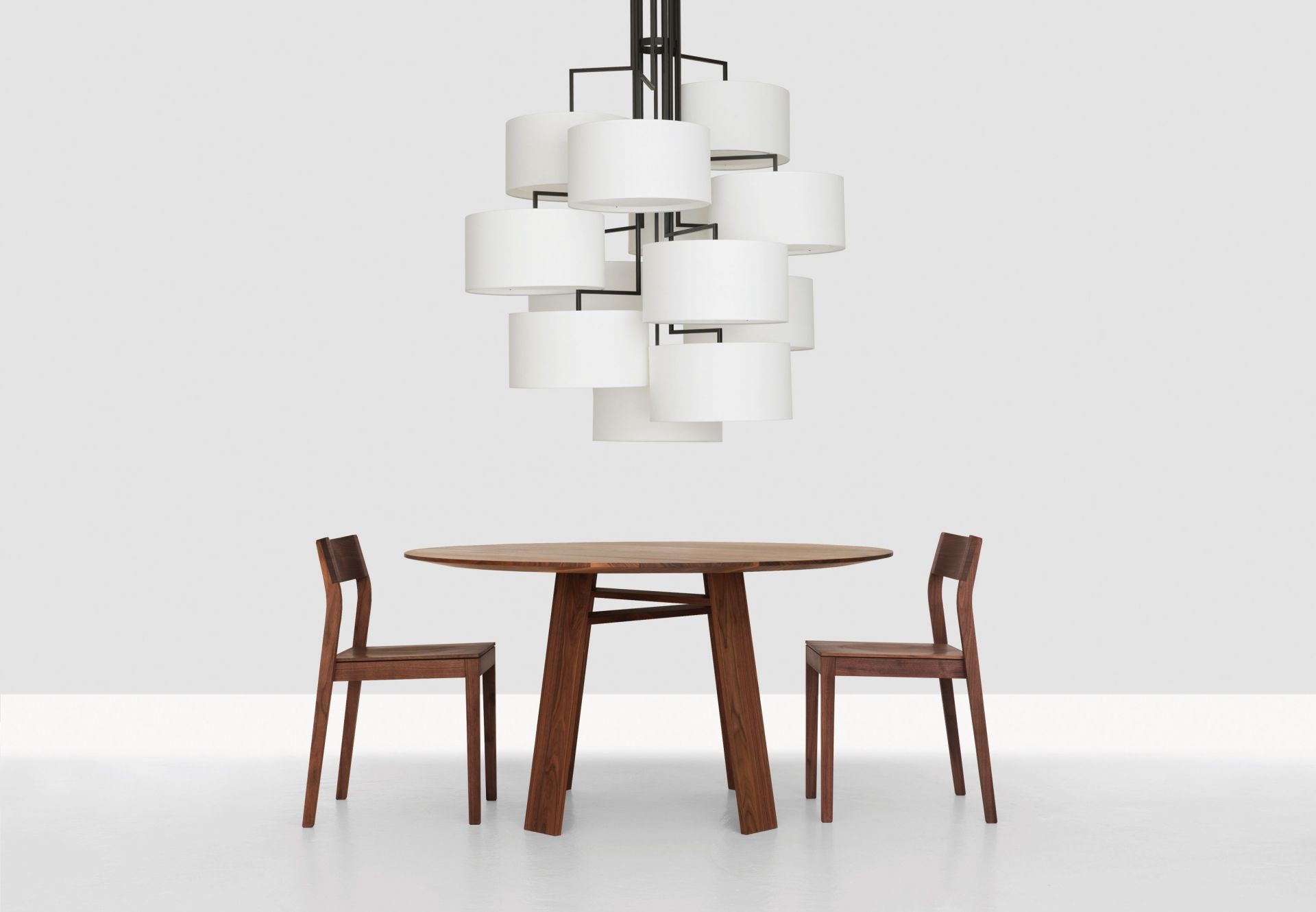 NOON 12 Deckenleuchte in Warmgrau über einem Esstisch mit zwei Holzstühlen. Moderne Beleuchtung.