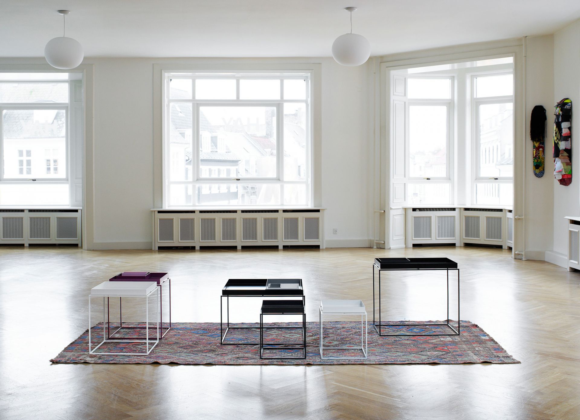 Helle Raumansicht mit vier Tray Table S Tischen von Hay in Schwarz, Weiß und Lila.