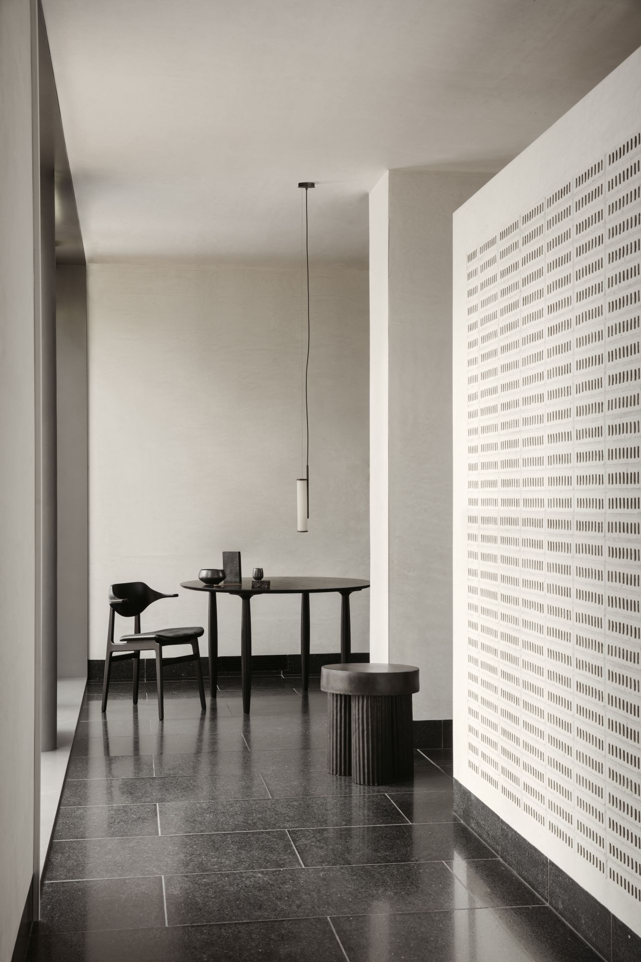Oku Esstisch rund Eiche schwarz Norr11 mit Stuhl und Hocker in minimalistischem Interieur.