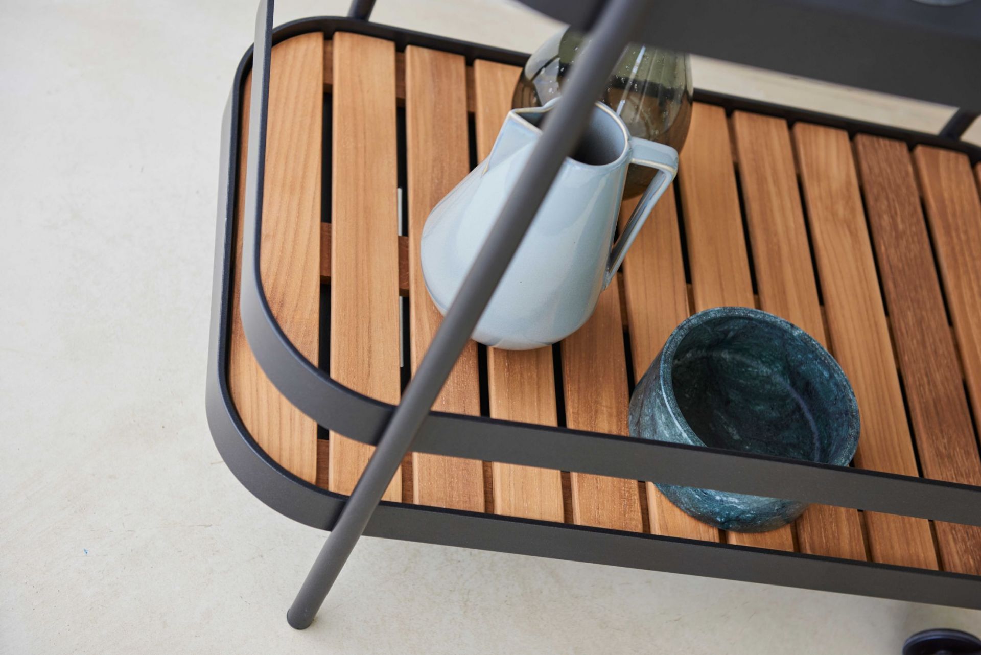 Detailaufnahme des Cane-Line Roll Barwagens in Lavagrau mit Holzablage und Dekoration. Keywords: Servierwagen, Gartenmöbel.