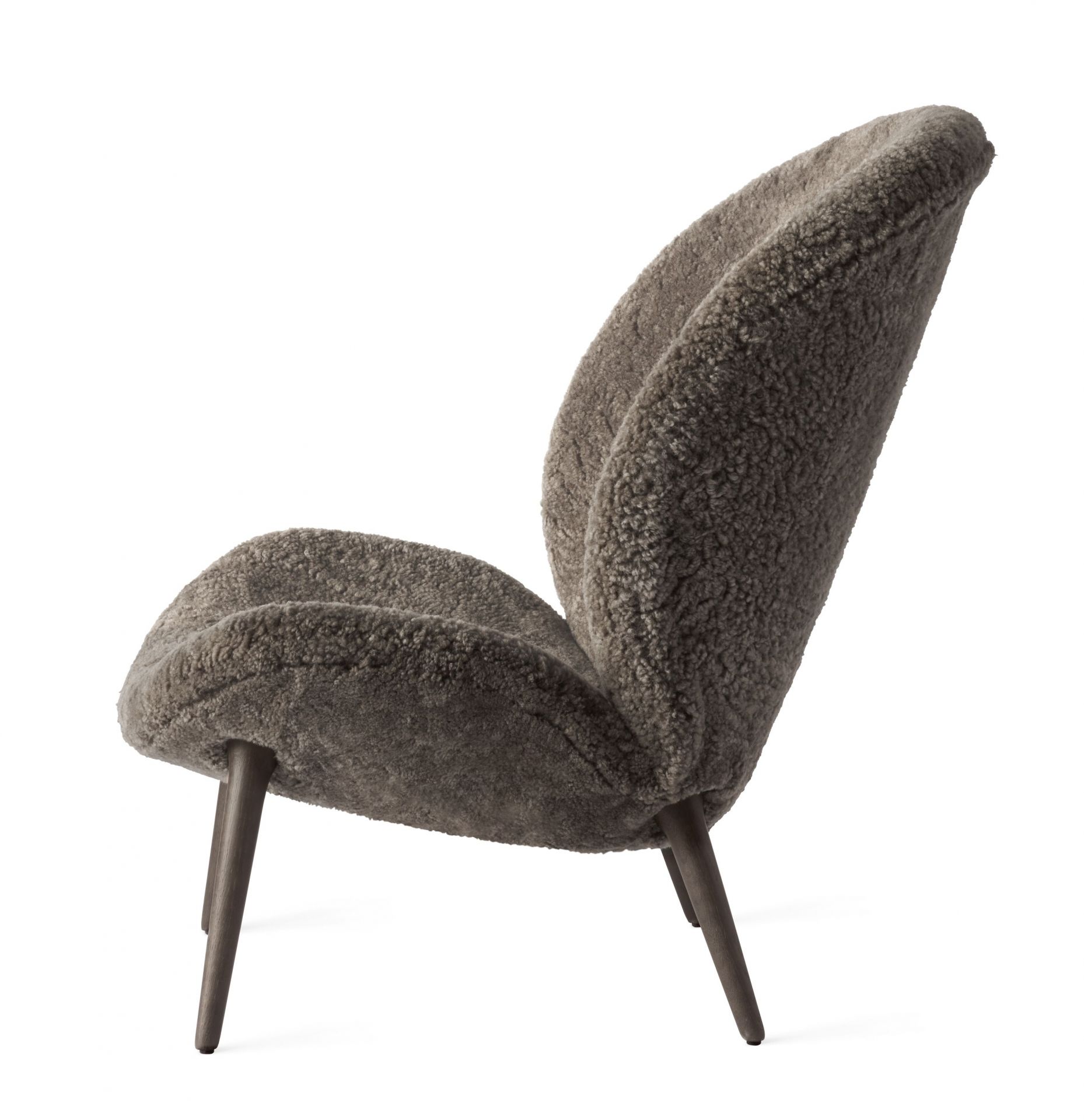Lodge Loungestuhl von Vipp, seitliche Ansicht. Gemütlicher Sessel mit grauem Schaffell und Holzfüßen.