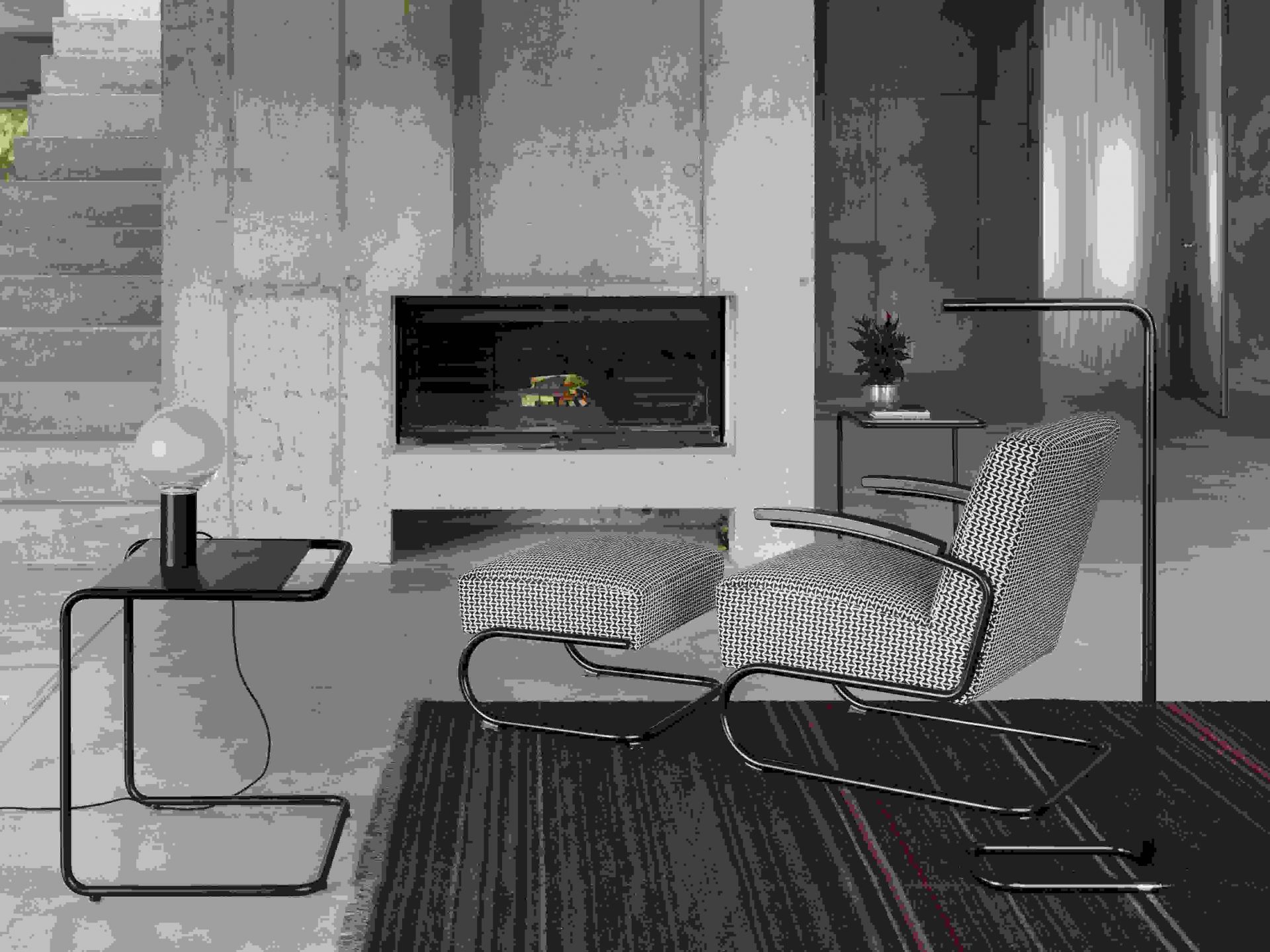 Lum LED Stehleuchte von Thonet, verchromt, im modernen Wohnzimmer mit Sessel und Kamin.