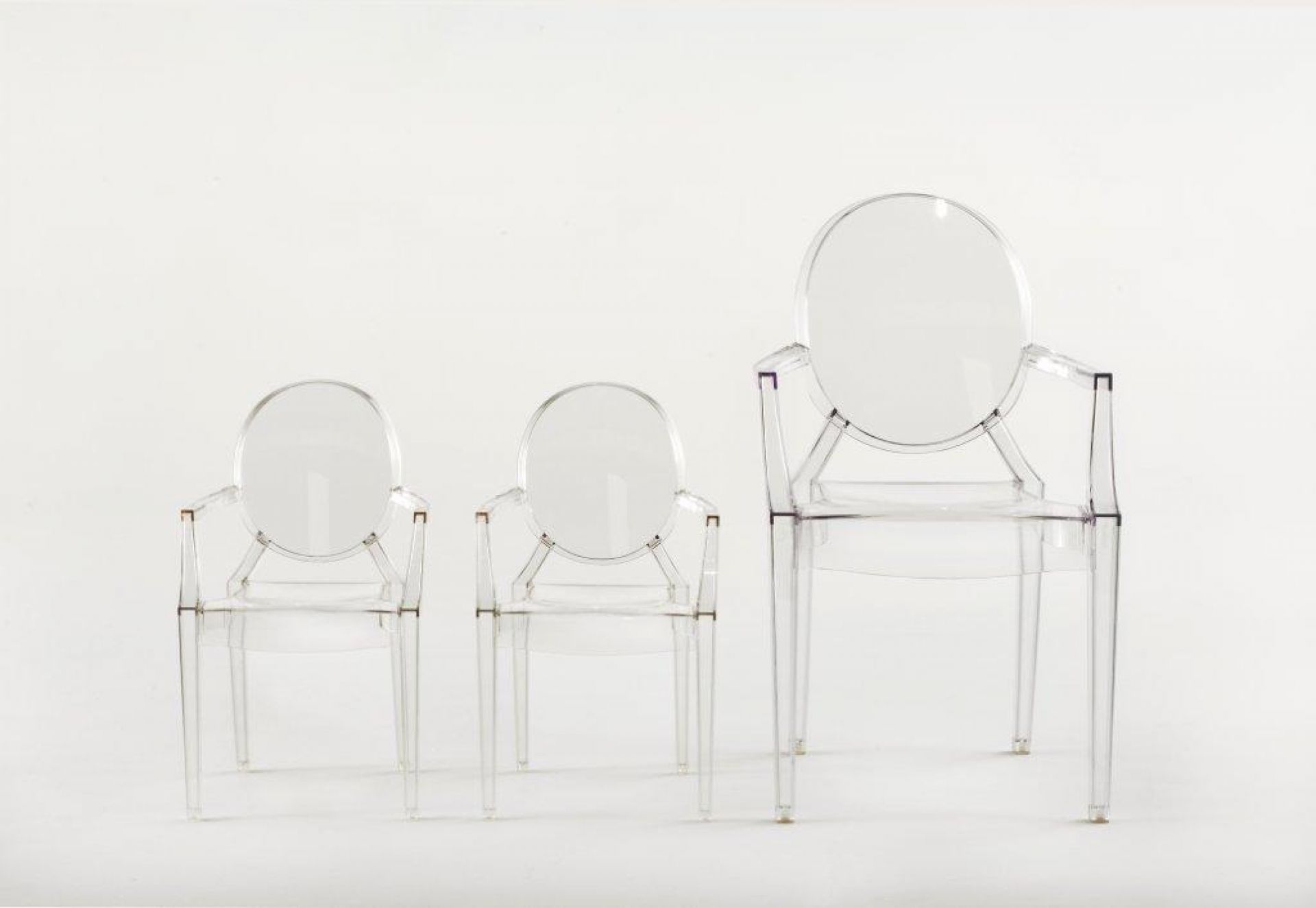 Drei transparente Lou Lou Ghost Kinderstühle von Kartell in verschiedenen Größen auf weißem Hintergrund.