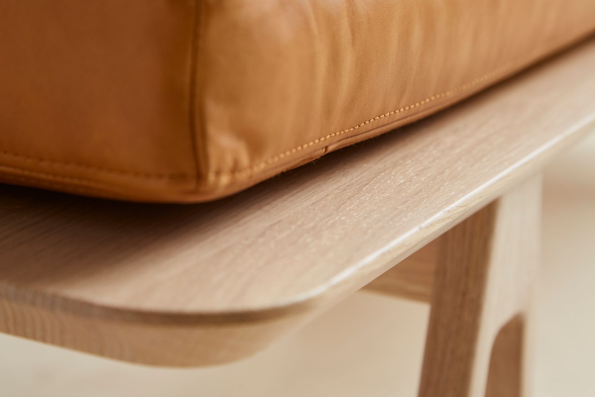 Detailaufnahme Level Daybed Liege von Woud: Cognacfarbenes Lederkissen auf hellem Eichenholzgestell.