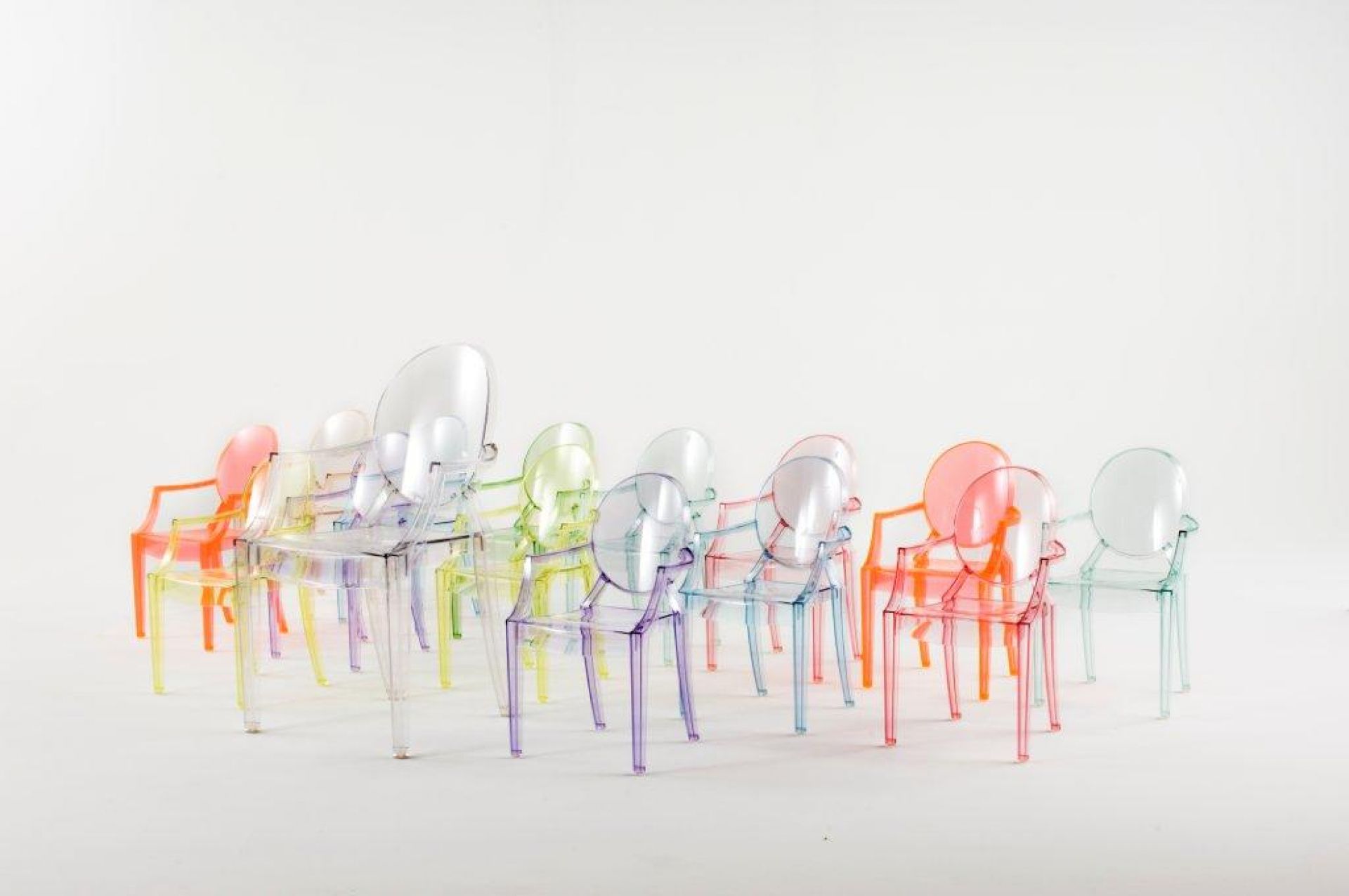 Mehrere Lou Lou Ghost Kinderstühle von Kartell in verschiedenen transparenten Farben auf weißem Hintergrund.