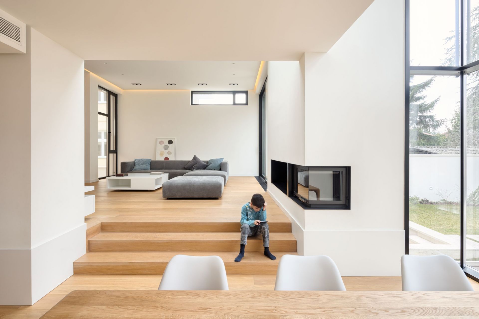 Heller Wohnraum mit grauem Match Sofa von Prostoria und Kind auf Holztreppe.