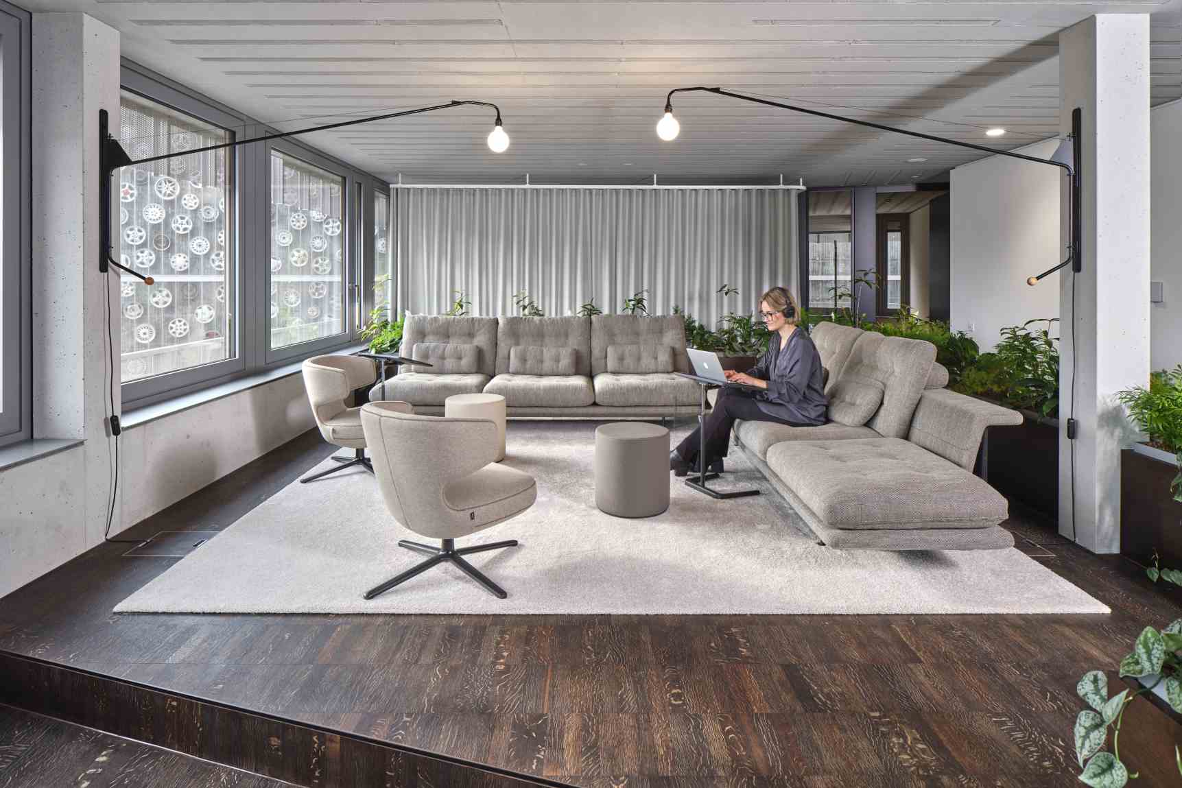 Helles Wohnzimmer mit Vitra Sofa, Sesseln und einer Frau, die auf dem Sofa arbeitet.