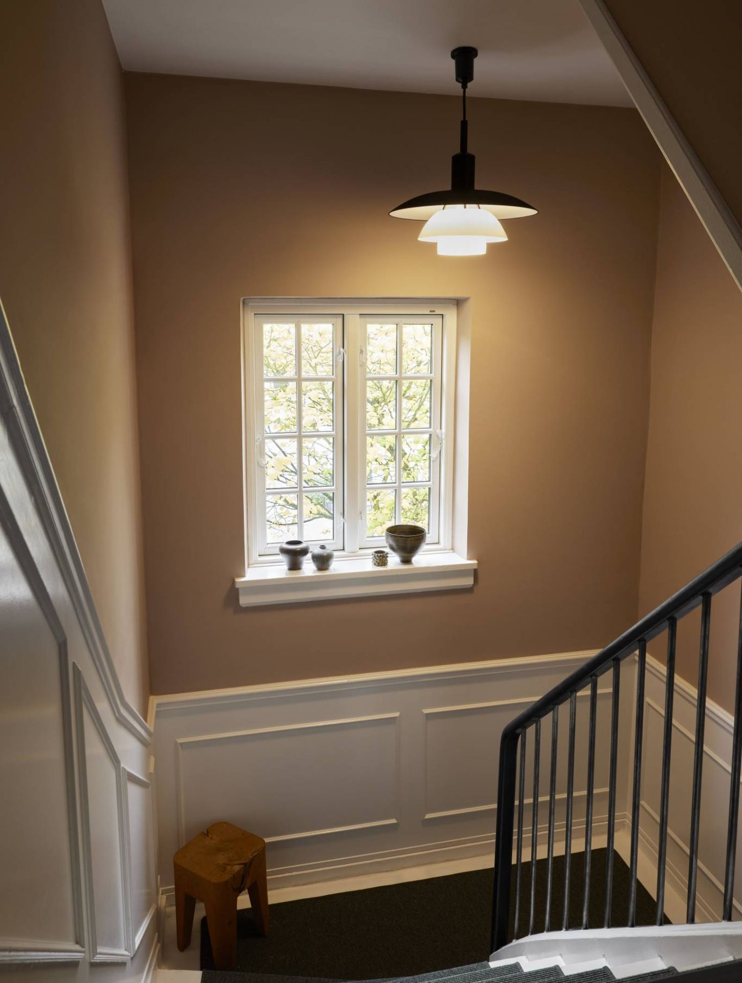 PH 5/5 Pendelleuchte von Louis Poulsen über Treppenhaus mit Fenster und Dekoration. Design Lampe.