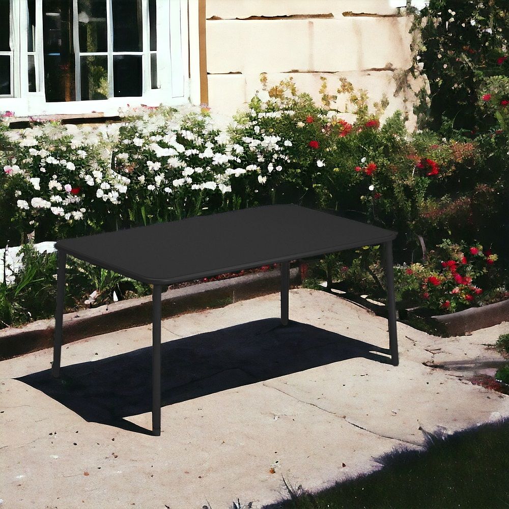 Schwarzer, rechteckiger Yard Tisch von emu im Garten vor einem Haus mit Blumenbeeten.