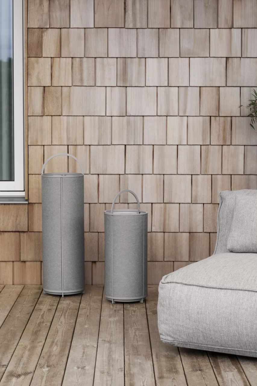 Zwei graue Blomus Grow Kissen, Outdoor-Möbel, auf einer Holzterrasse vor einer Holzwand.