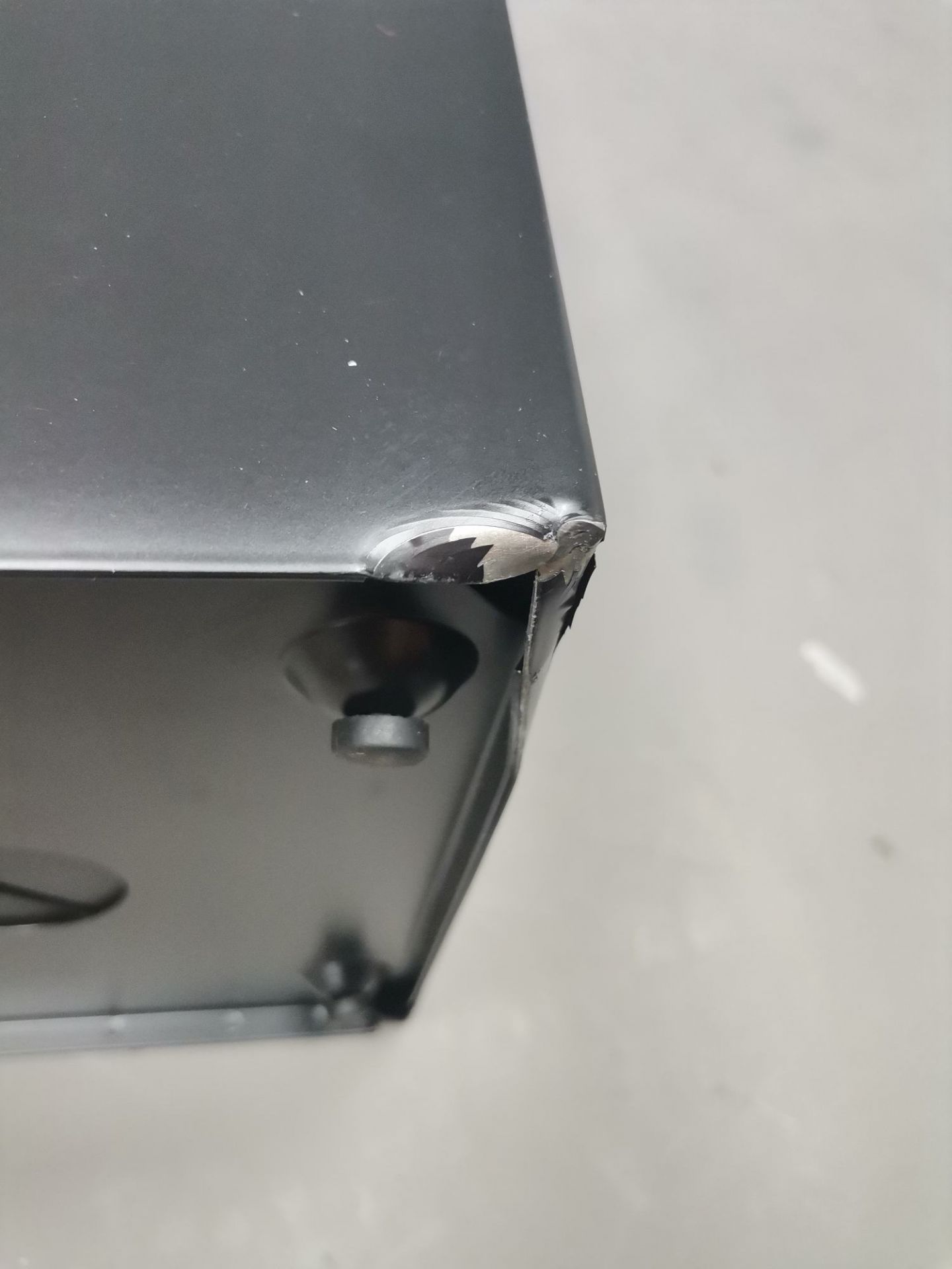 Detailaufnahme des beschädigten, schwarzen Via Schirmständers: Ecke verbogen, Mängelexemplar, ideal für Eingangsbereich.