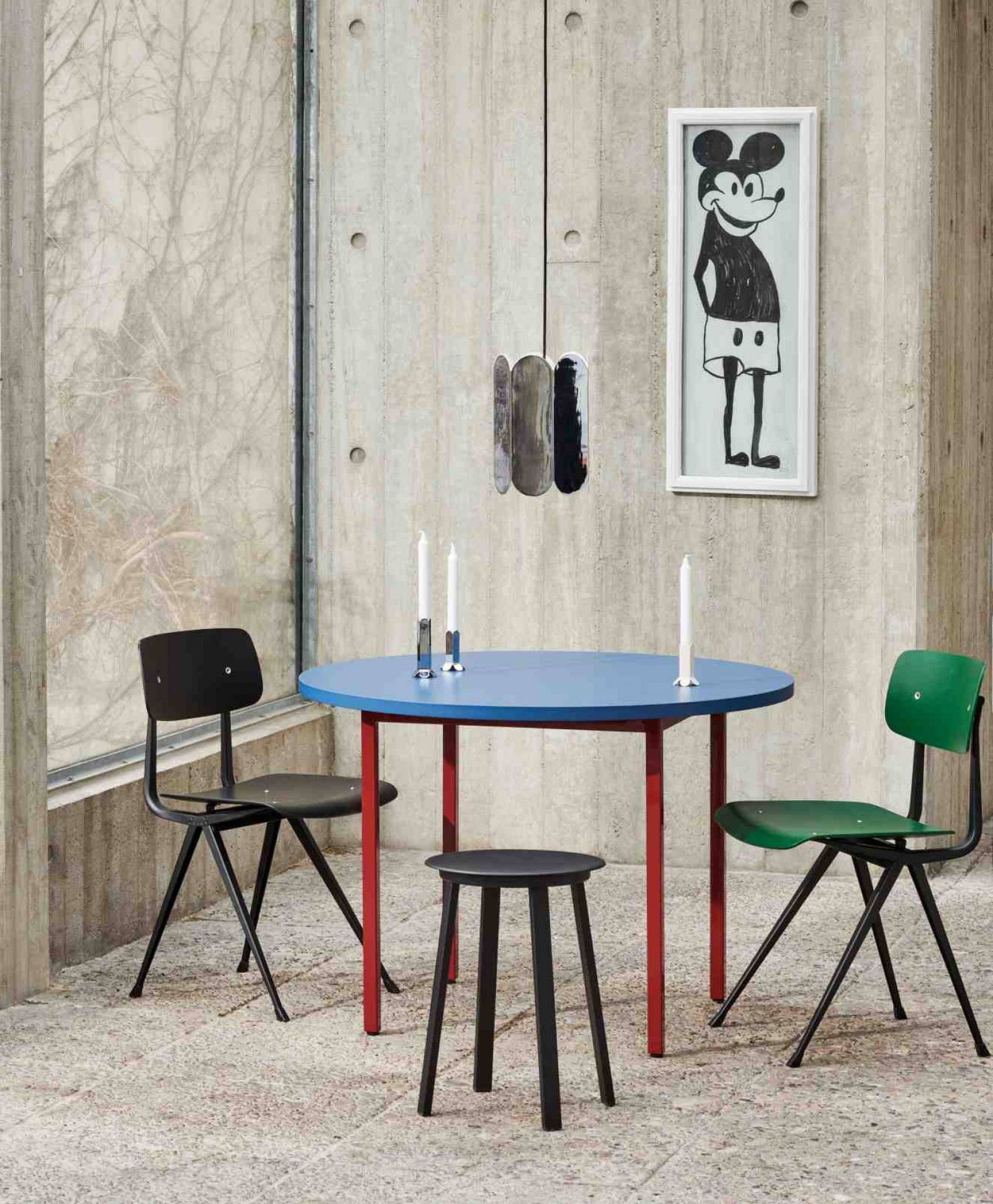 Blauer Hay Two Colour Table Tisch mit roten Beinen, umgeben von Stühlen und einem Hocker.