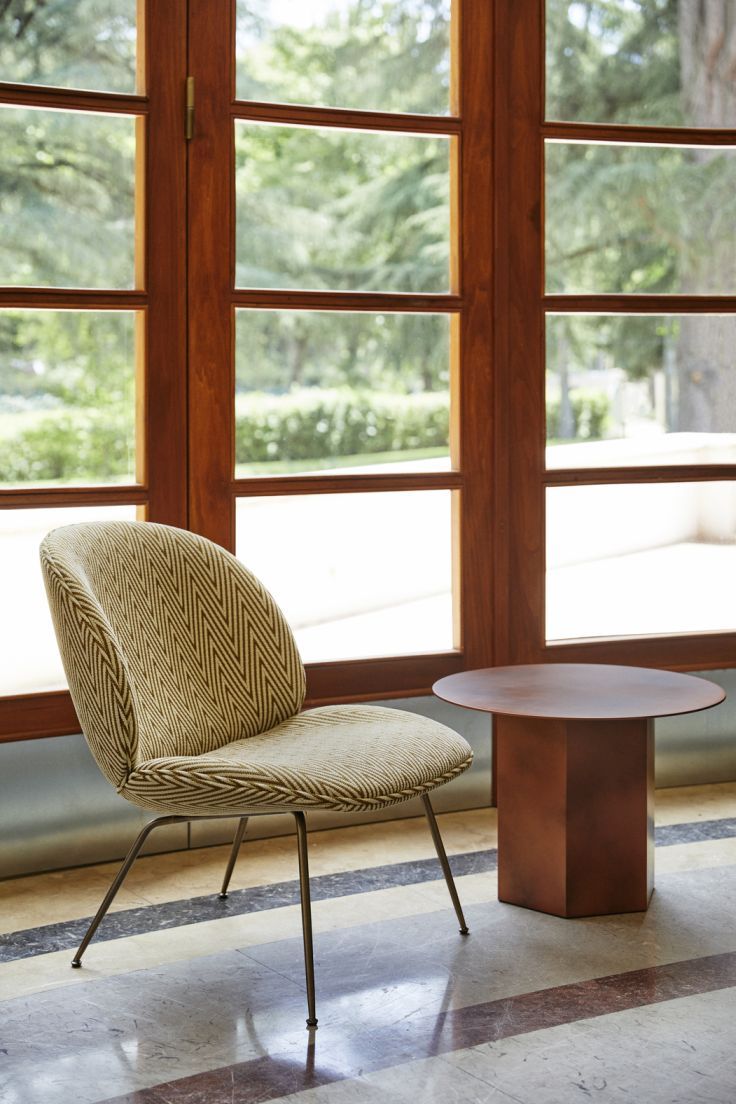 Epic Coffee Table Couchtisch 60 Earthy Red Stahl Gubi neben einem Stuhl vor einem Fenster.