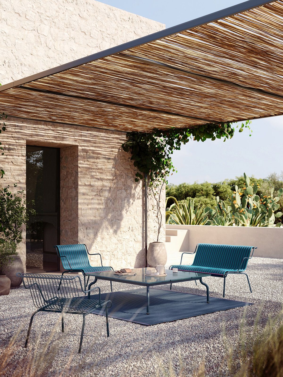 Gartenmöbel-Set aus Tisch, Stühlen und Bank unter einer Pergola im mediterranen Stil.