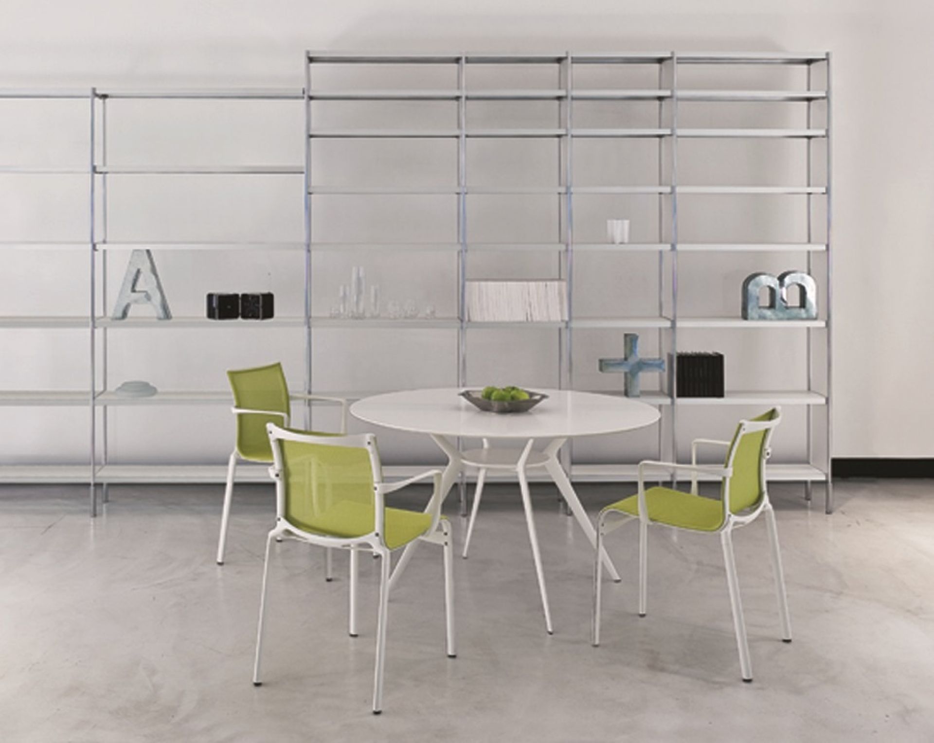 Weißer Biplane Tisch von Alias mit grünen Stühlen vor einem Regal. Outdoor-Möbel für Garten und Terrasse.