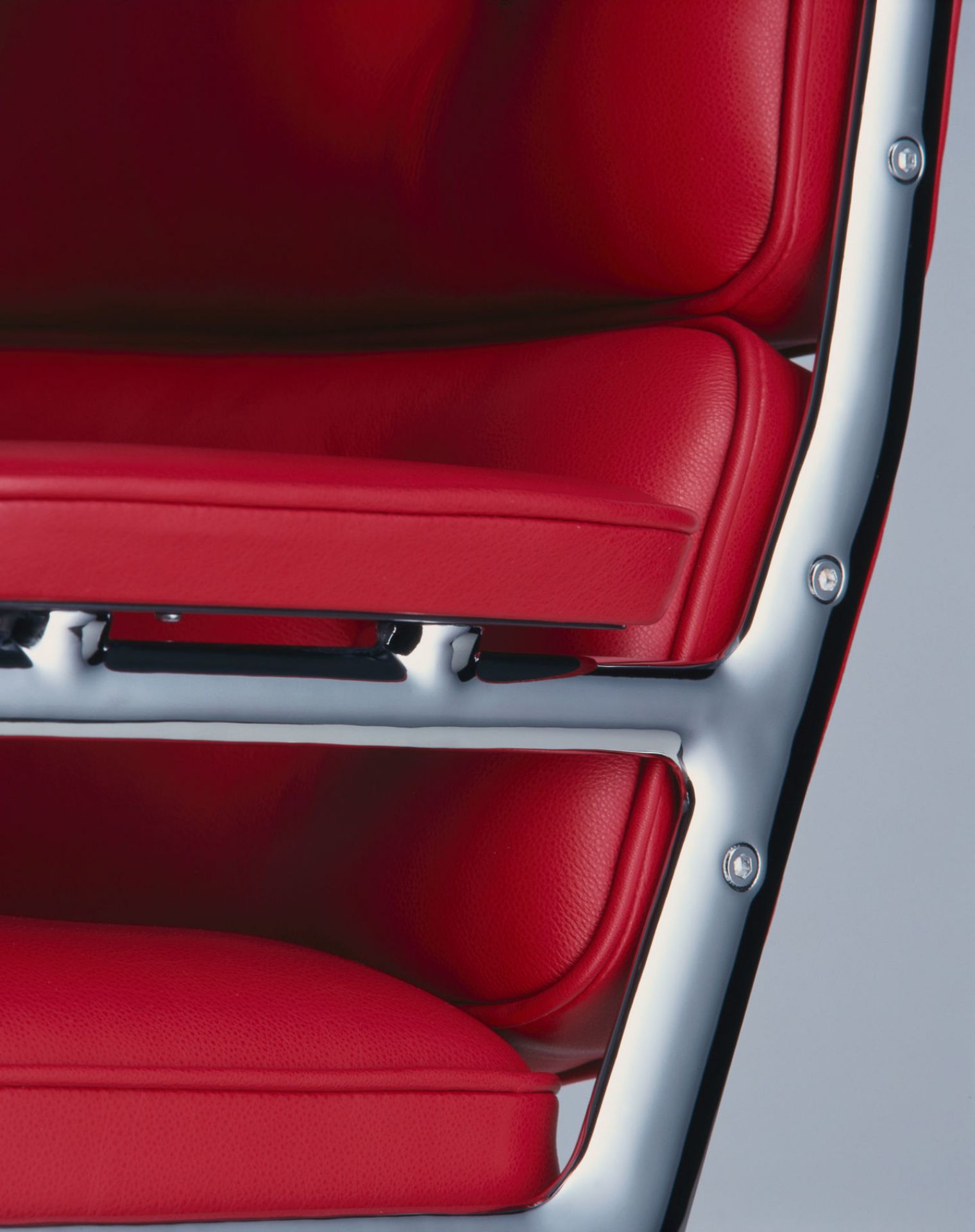 Detailaufnahme: Roter Lederbezug und verchromtes Gestell des Vitra Lobby Chair ES104 Stuhls.
