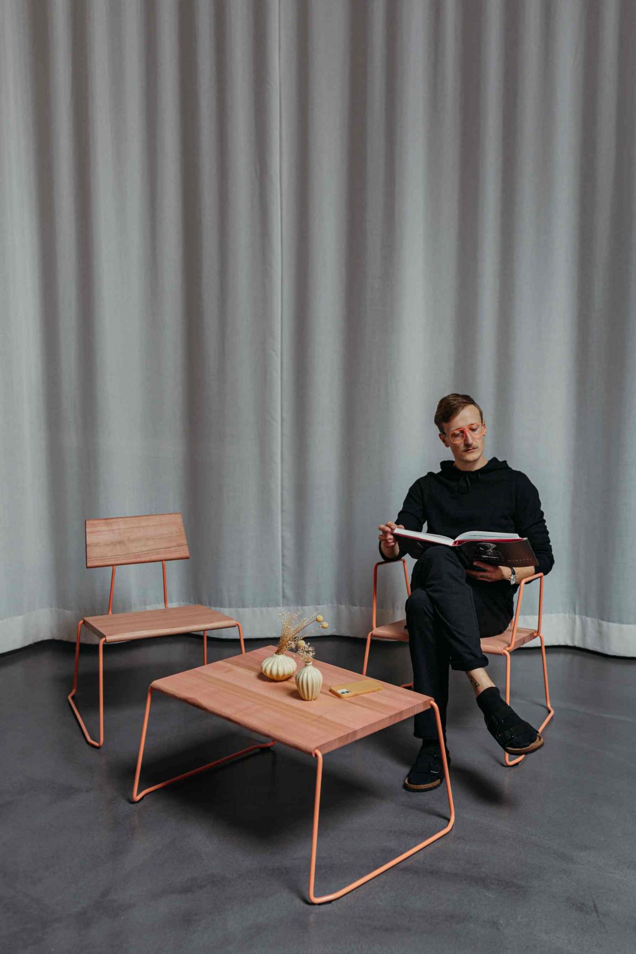 Mann liest am D:009 Coffeetable von Fuchs & Habicht. Moderner Couchtisch mit Holzplatte.