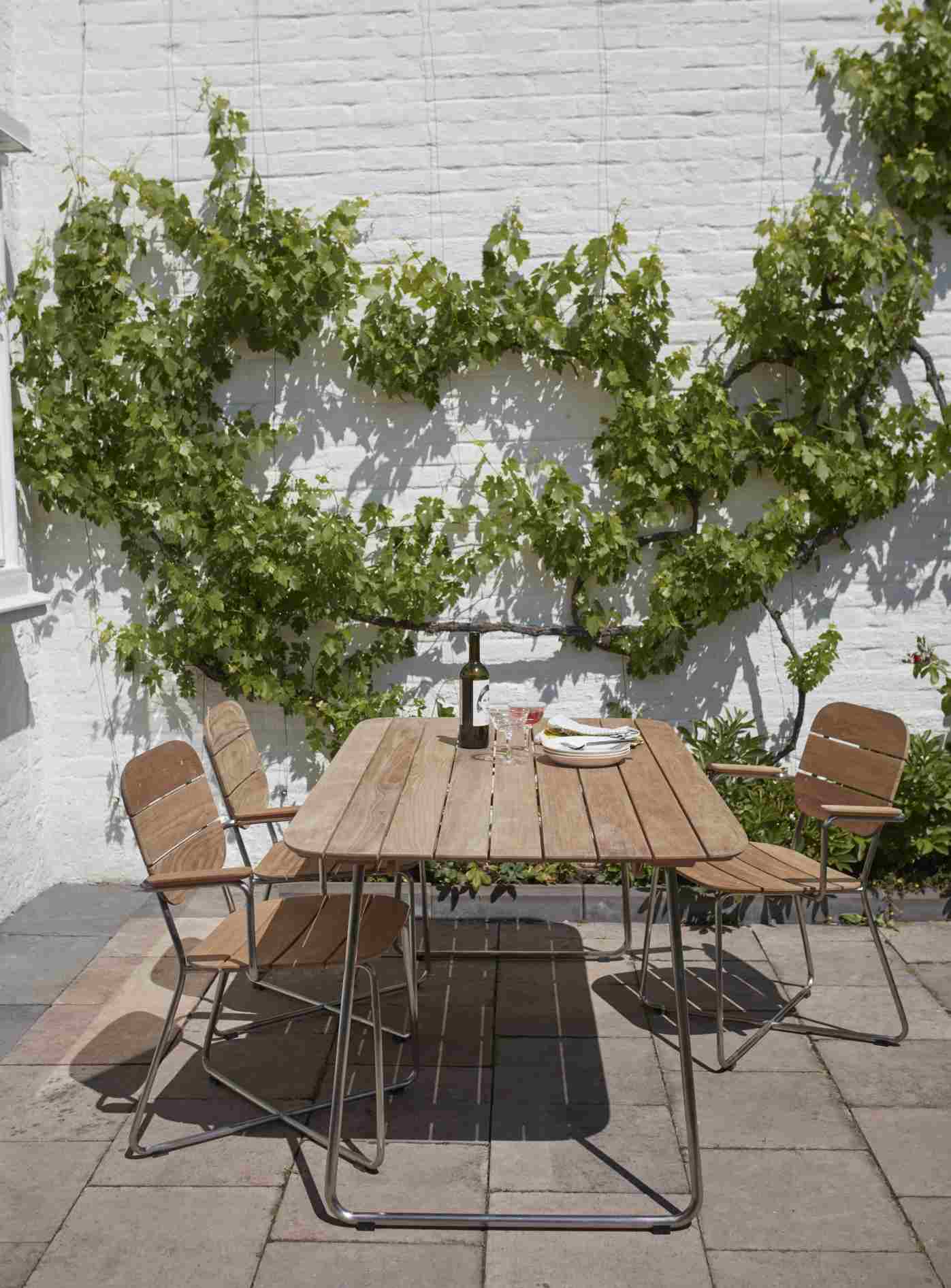 Lilium Armchair Armlehnenstuhl von Skagerak by Fritz Hansen auf Terrasse mit Esstisch und Wein.