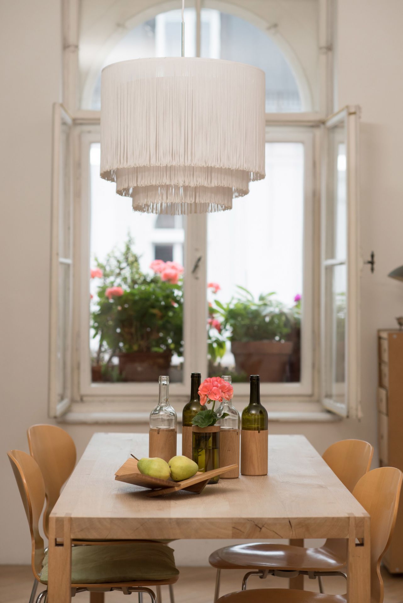 WeinWindlicht Side by Side Glas grün auf Esstisch mit Birnen und Blumen vor Fenster.