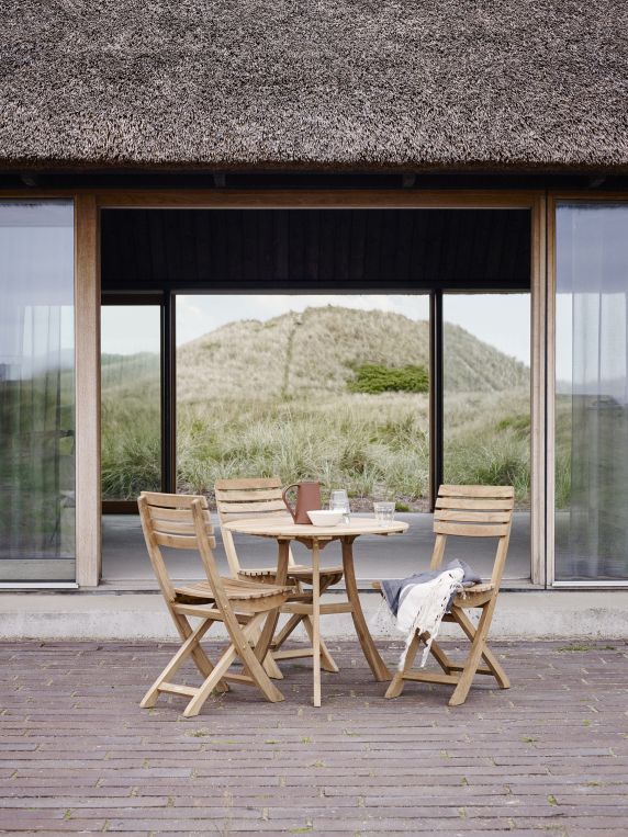 Vendia Tisch von Skagerak by Fritz Hansen mit Stühlen im Außenbereich vor Dünenlandschaft.