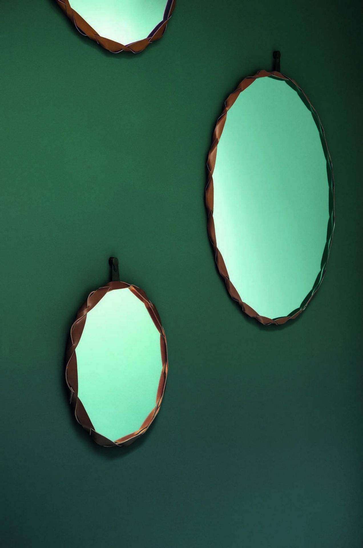 Drei runde Raperonzolo Spiegel von Zanotta mit geflochtenem Lederrahmen an einer grünen Wand.