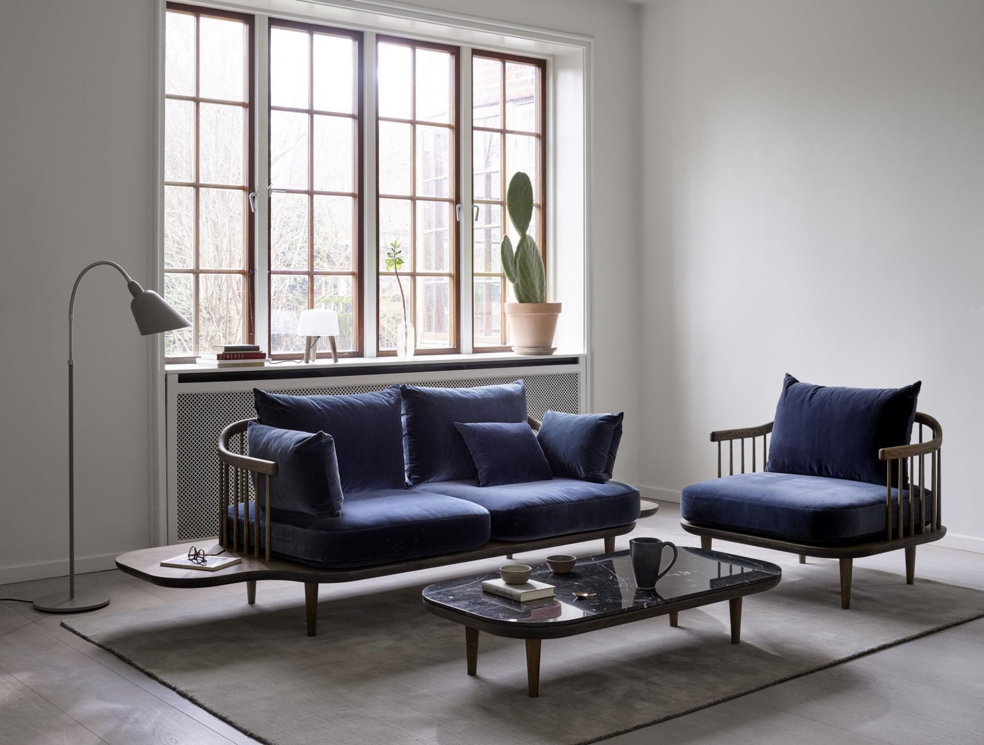 Wohnzimmer mit AndTradition Bellevue AJ7 Stehleuchte in Grau, neben blauem Sofa und Sessel.