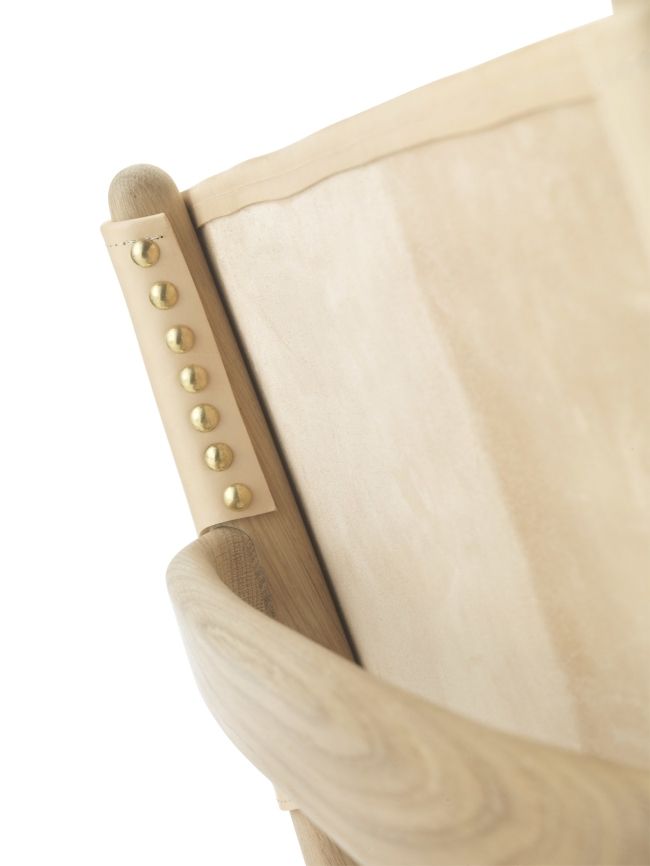 Detailaufnahme des Saxe Chair: Helles Holzgestell mit Lederriemen und goldenen Nieten. Design Stuhl.