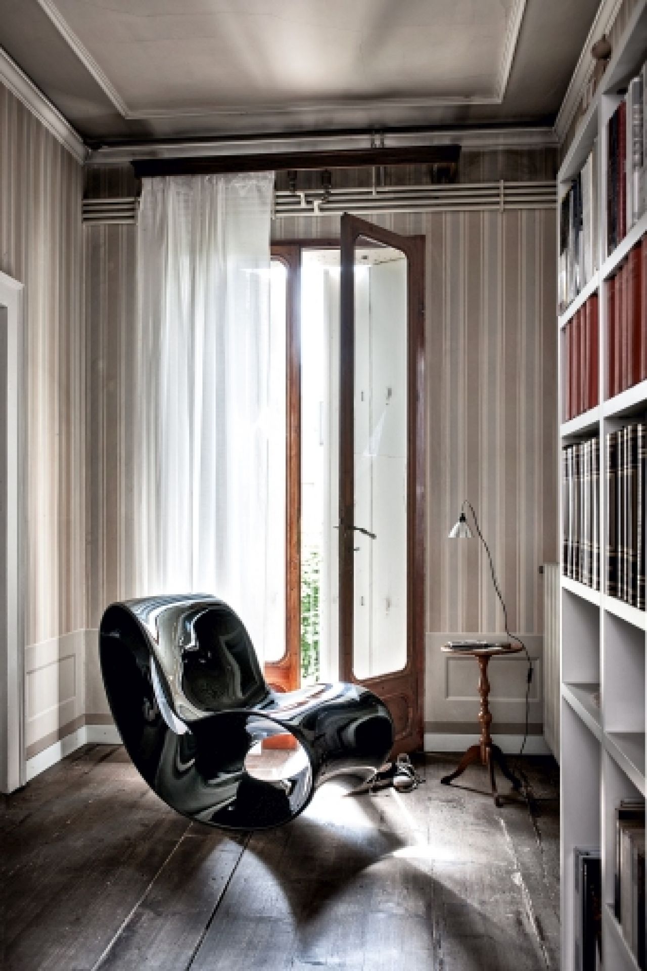 Schwarzer VOIDO Schaukelstuhl von Magis in einem stilvollen Wohnzimmer mit Holzboden und Bücherregal.