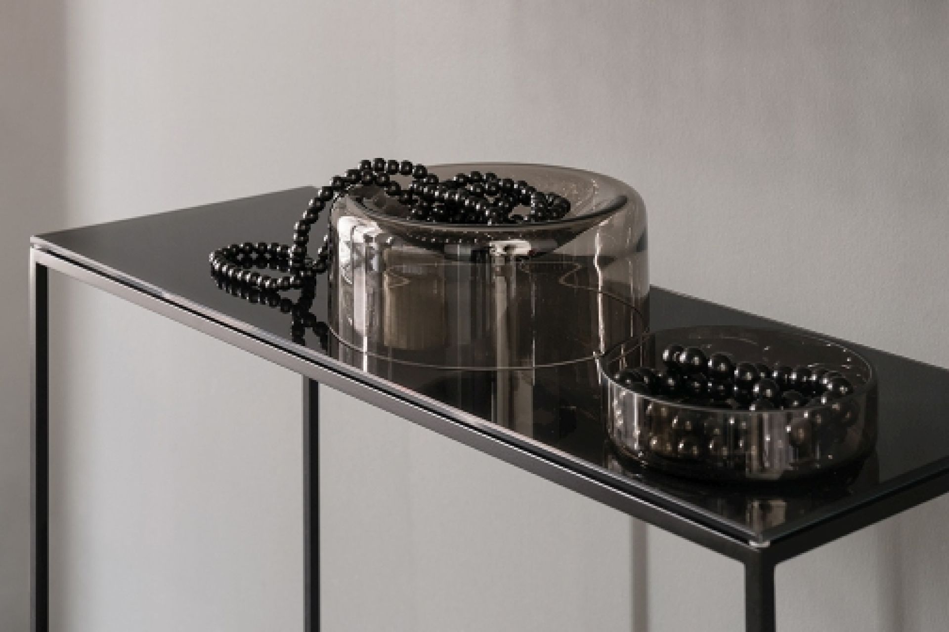 Schwarzer Rack Konsoltisch von Schönbuch, 70 cm breit, mit dekorativen Glasobjekten und Perlenketten.