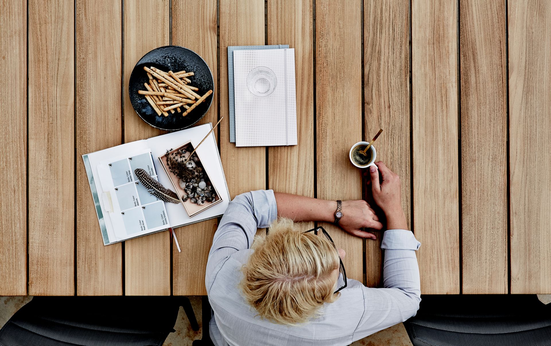 Draufsicht auf den Core Outdoor Esstisch von Cane-Line aus Teakholz mit Dekoration und Person.