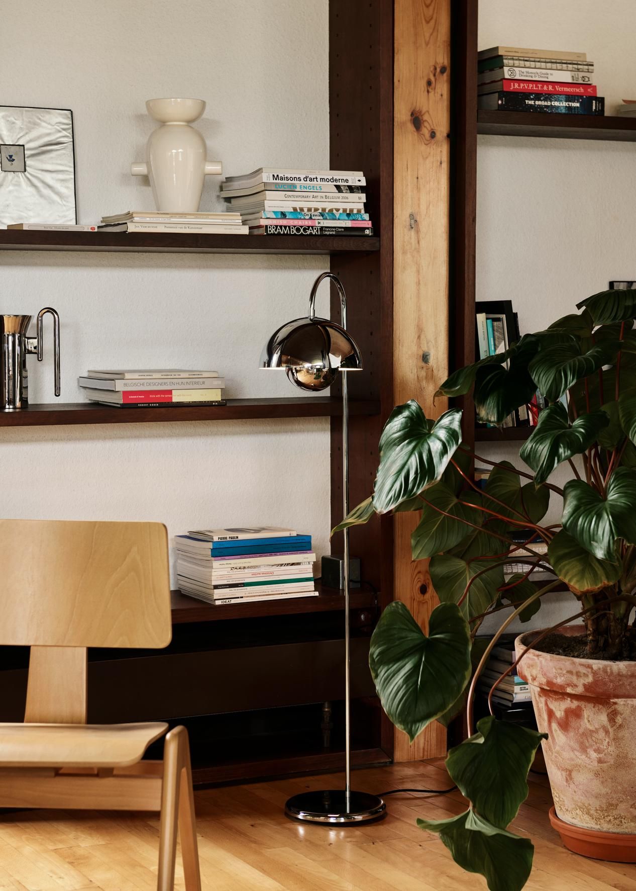 Flowerpot Stehleuchte VP12 von AndTradition in Chrom vor Bücherregal und Zimmerpflanze.
