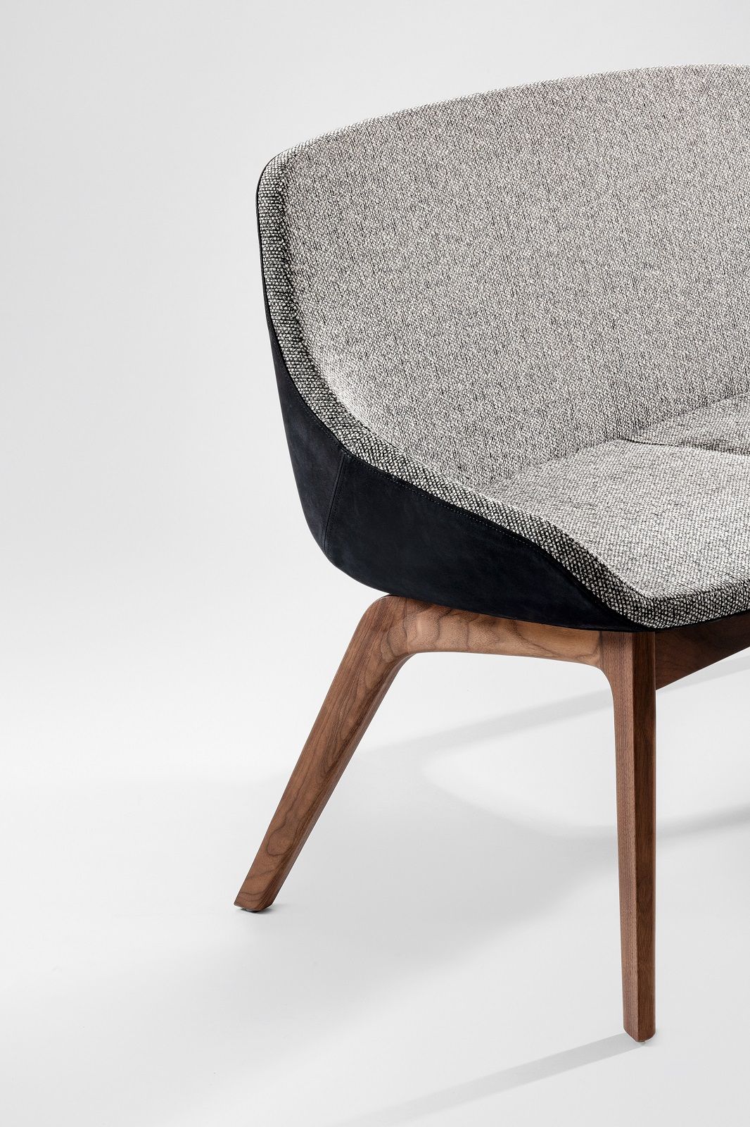 Detailaufnahme des Morph Duo Dining Sofas: Grau melierter Stoffbezug, schwarze Akzente und Holzbeine.