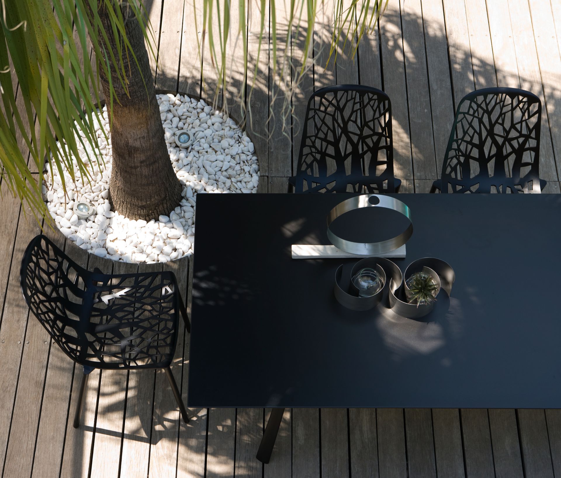 Draufsicht: Schwarze Forest Outdoor Stühle mit Baumdesign auf Holzterrasse, Gartenmöbel für den Außenbereich.