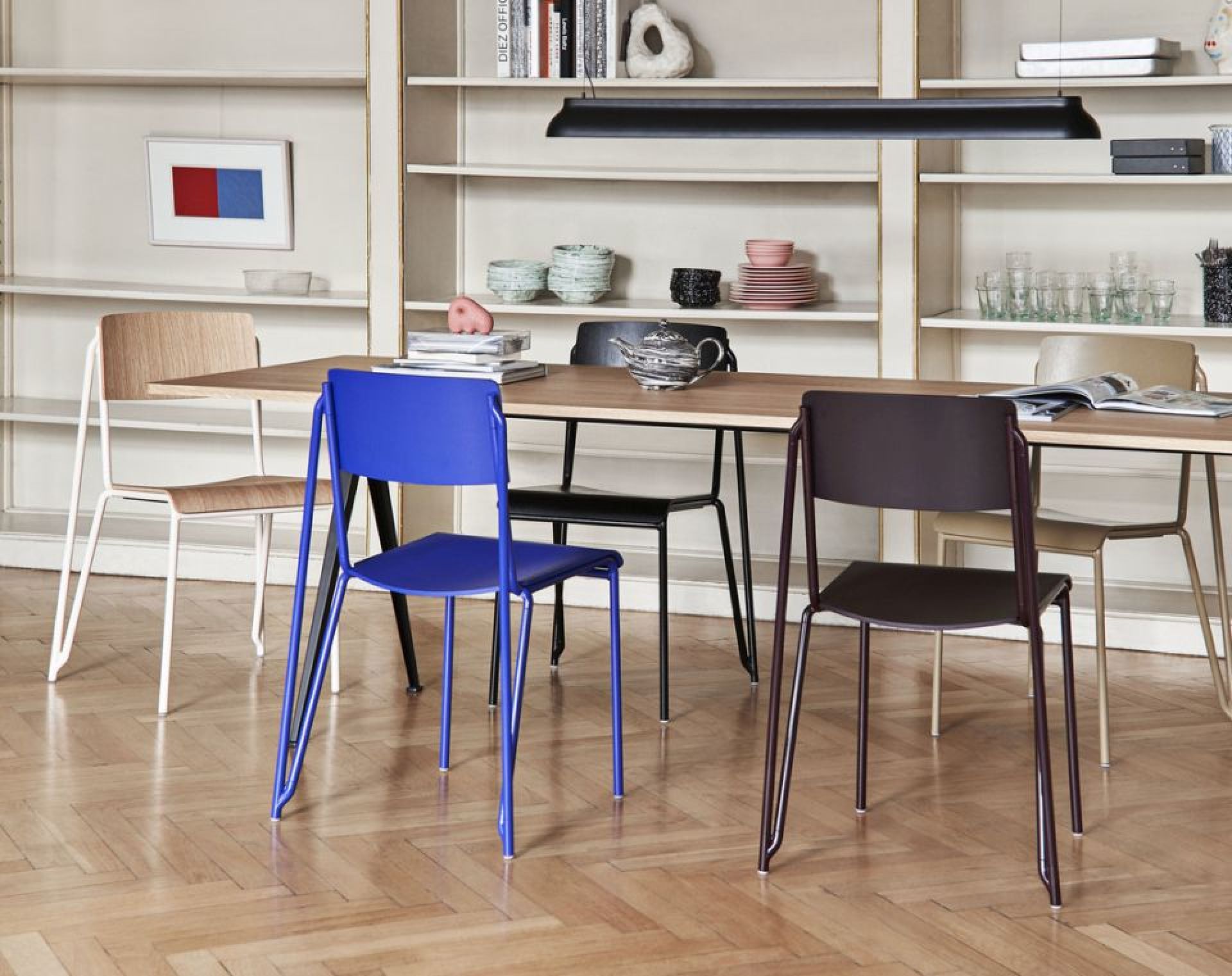 Mehrere Hay Petit Standard Stühle in verschiedenen Farben um einen Holztisch in einem Esszimmer.