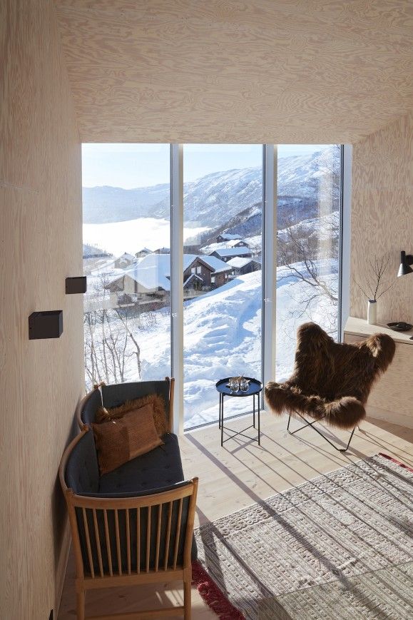 Wohnzimmer mit Iceland Mariposa Butterfly Sessel aus Schaffell in Braun und Blick auf Winterlandschaft.