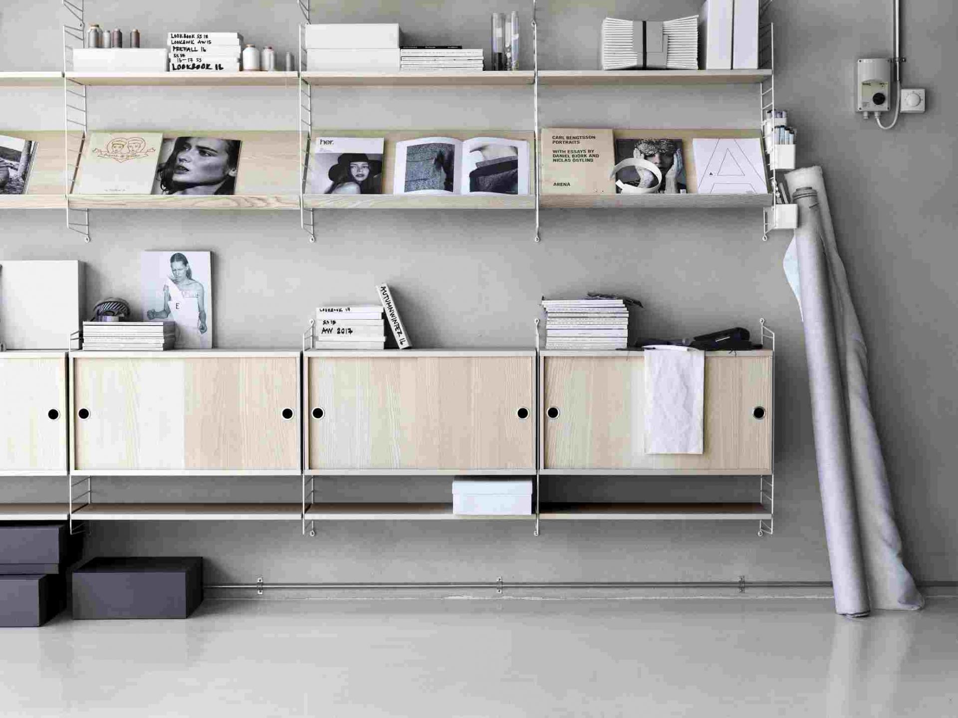 String Regalsystem mit Holzablagen und Schränken an grauer Wand, modernes Wohnzimmer Design.