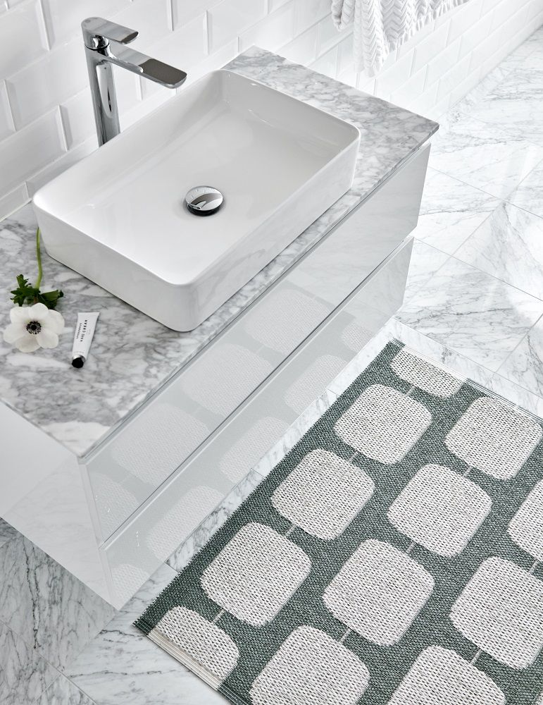 Sten Kunststoffteppich in Army/Fossil grau (Pappelina) neben einem Waschbecken im Badezimmer. Muster: Quadrate.