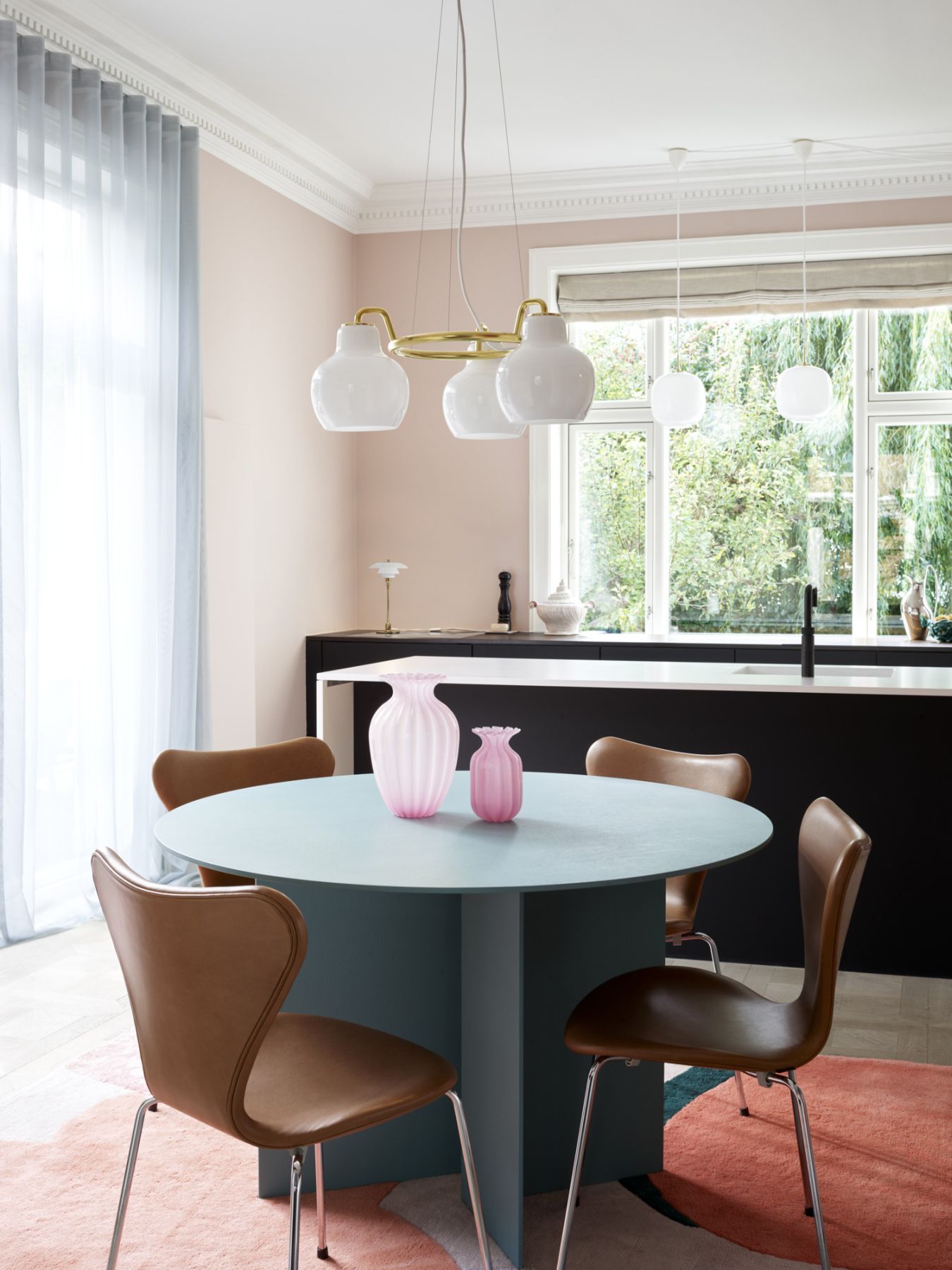 Esszimmer mit Louis Poulsen VL Ring Crown Pendelleuchte, Esstisch, Stühlen und rosa Vasen.