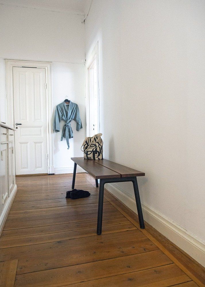 Emeco Run Bench Bank mit Walnuß-Sitzfläche und schwarzem Gestell im Flur. Design Sitzbank.