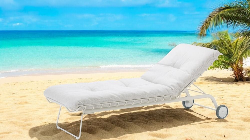 Weiße Leyasol Sonnenliege von Freifrau Manufaktur am Strand mit Meer und Palmen im Hintergrund.