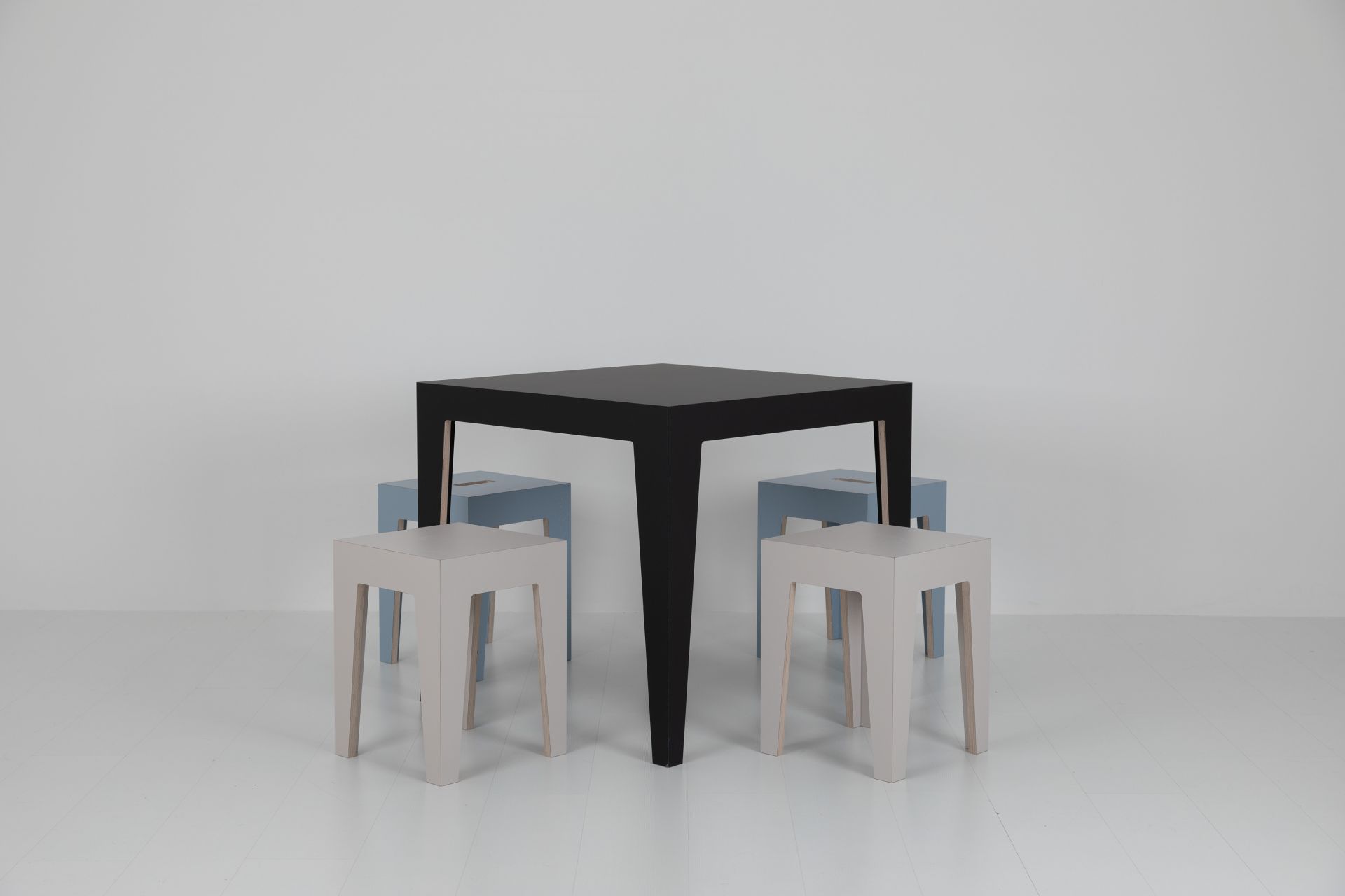 Schwarzer MARTA Holztisch mit vier Hockern in Grau und Blau vor weißem Hintergrund.