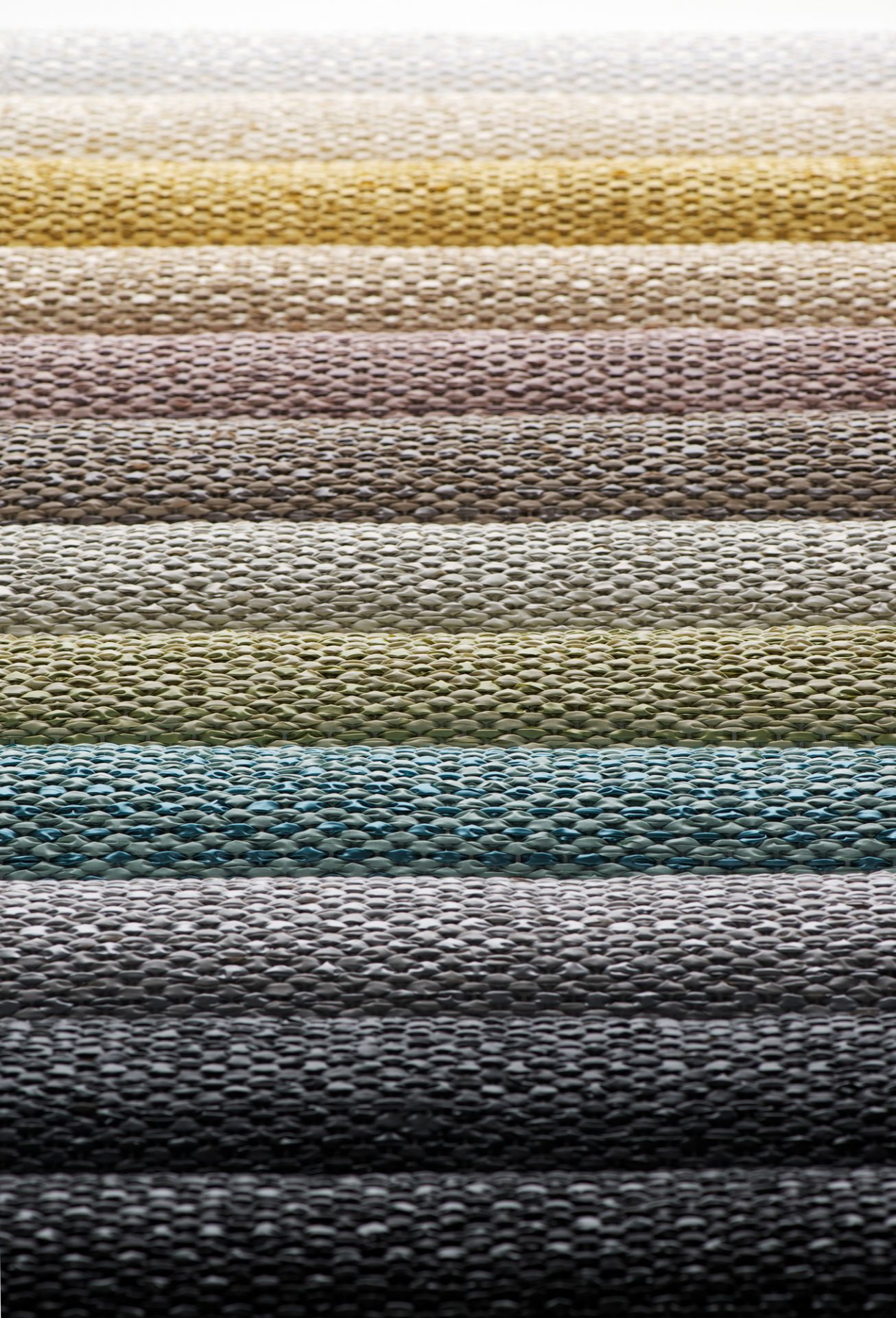 Detailaufnahme verschiedener Farbvarianten des Svea Kunststoffteppichs von Pappelina. Teppichmuster in Schlamm- und Erdtönen.