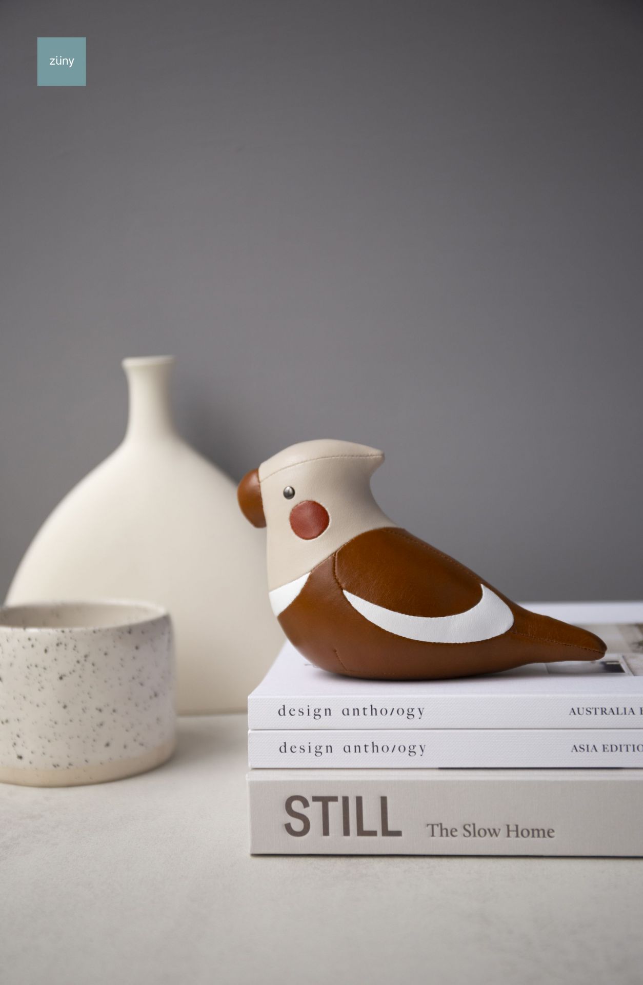 Züny Nymphensittich Briefbeschwerer in Tan und Weizen auf Bücherstapel, dekoratives Wohnaccessoire.