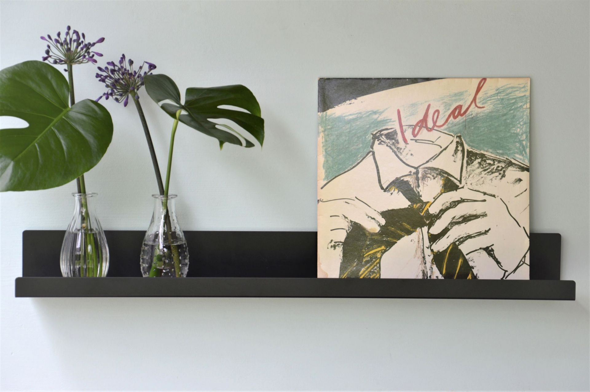 Schwarzes Jill Wandregal von Jan Kurtz mit Deko: Vasen, Pflanzen und Schallplatte.