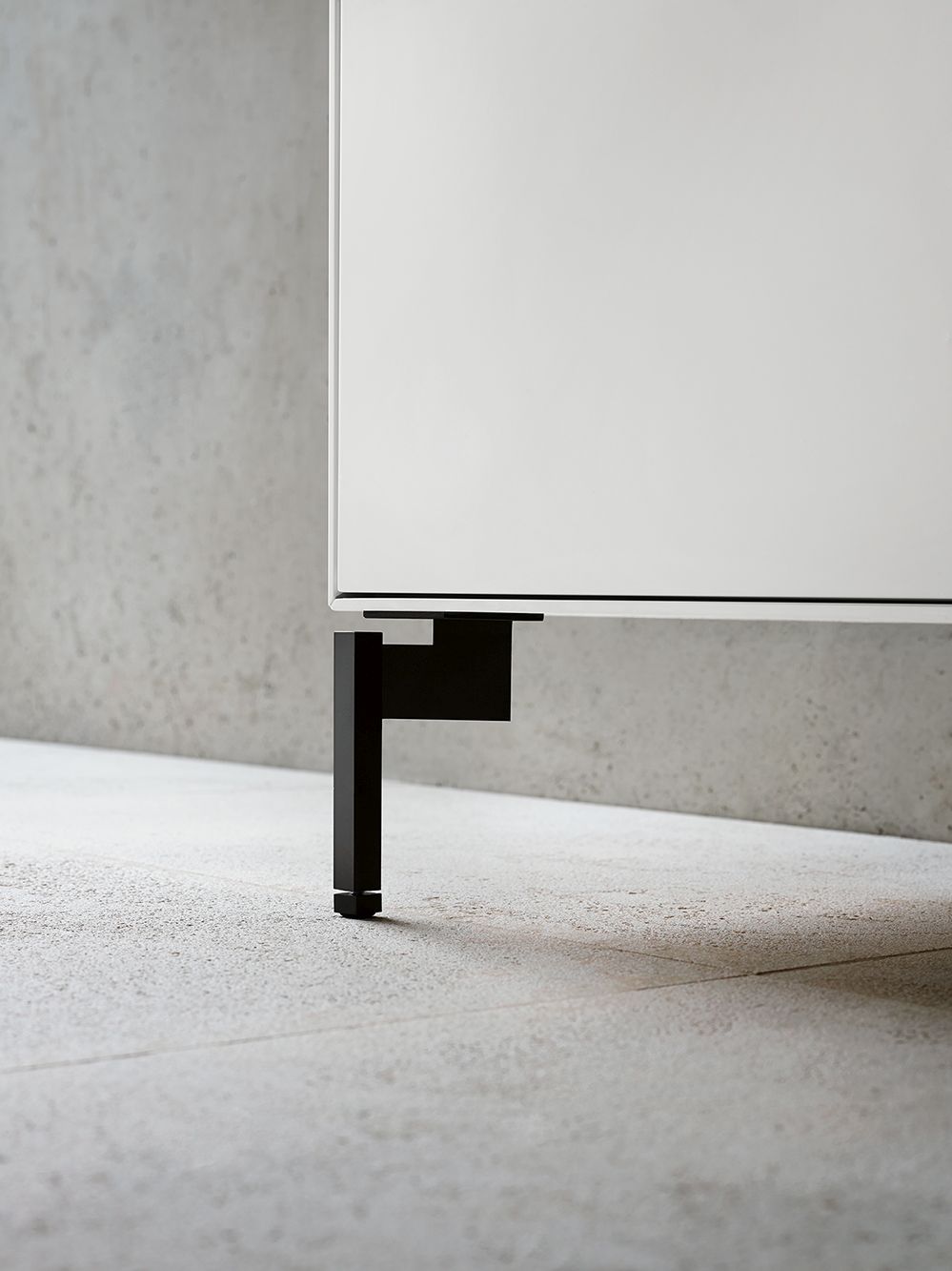 Detailaufnahme: Schwarzer Fuß des weißen Piure Nex Pur Box TV-Lowboards.