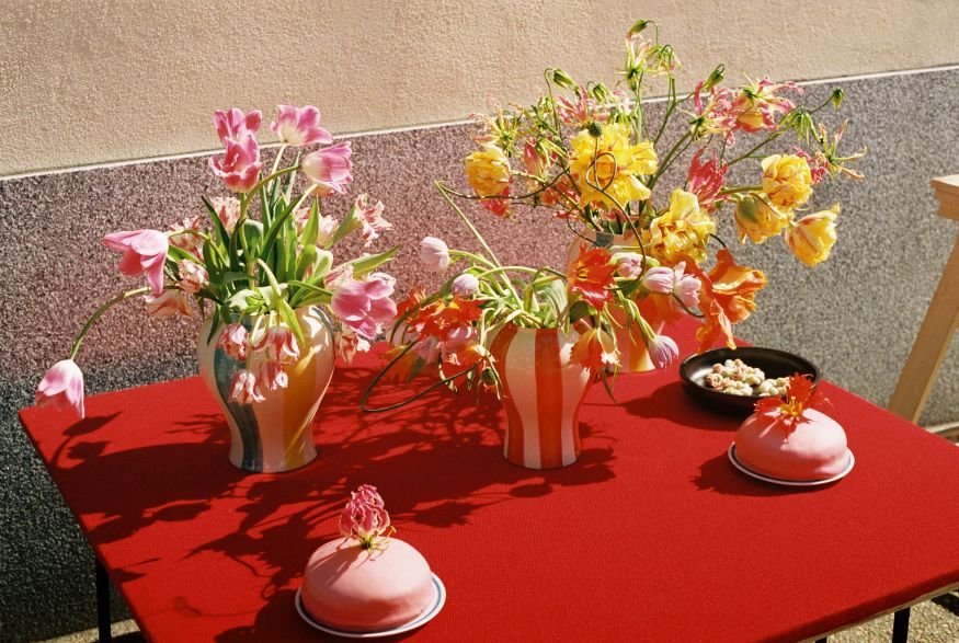 Rote Sobremesa Strip Vase von Hay mit Blumen auf einem roten Tisch. Dekorative Keramik Vase.