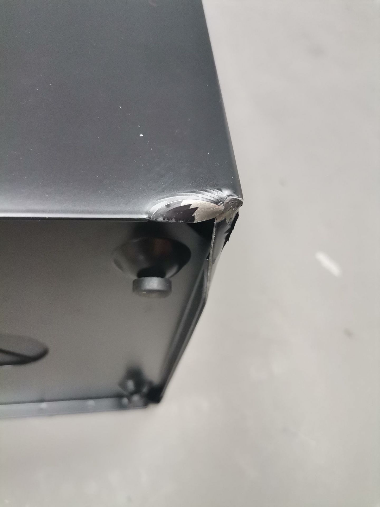 Detailaufnahme: Beschädigung an der Ecke des schwarzen Via Schirmständers, ein Mängelexemplar mit Lackschaden.