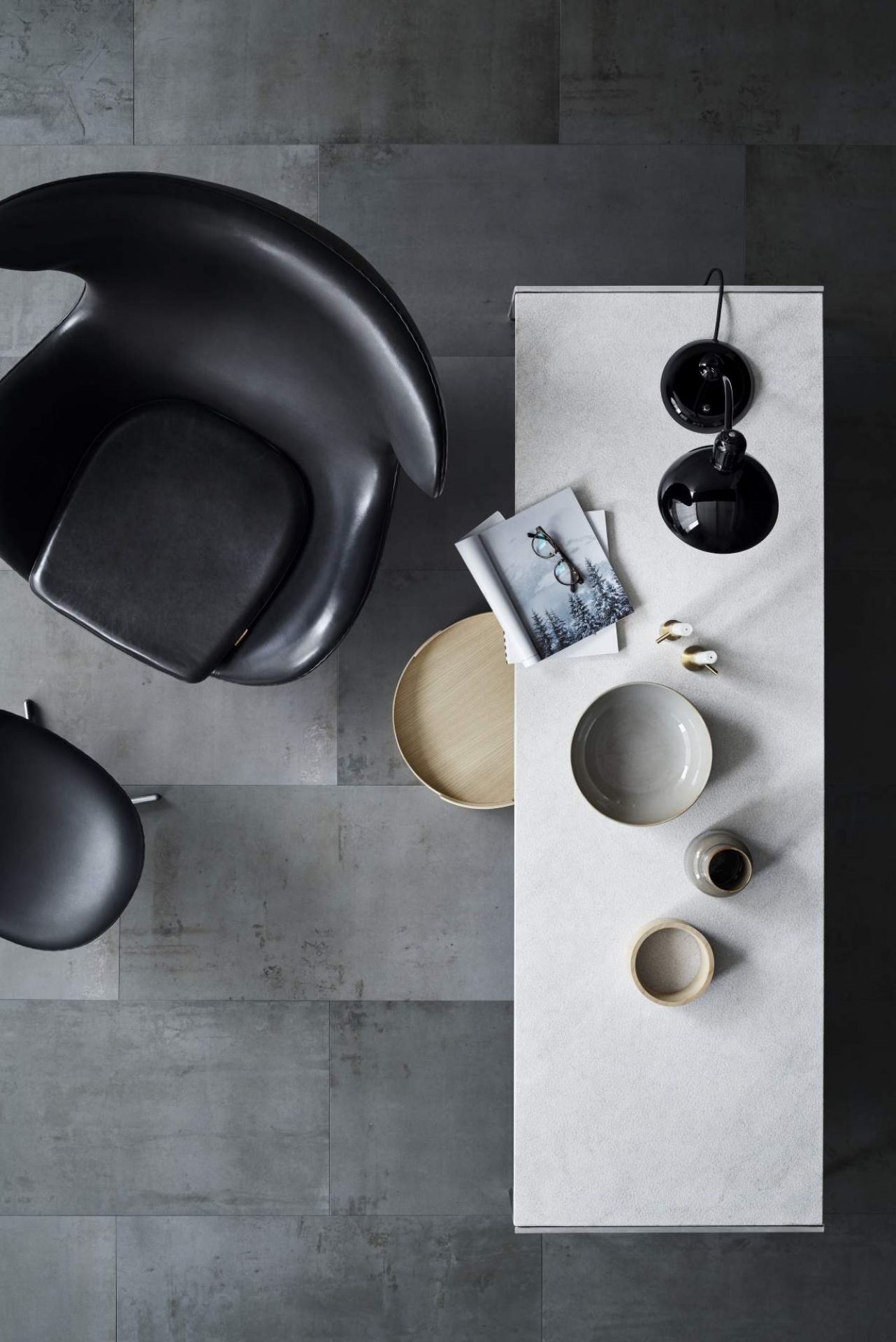 Draufsicht: PK63 Esstisch von Fritz Hansen mit Designobjekten und schwarzen Sesseln auf grauem Boden.