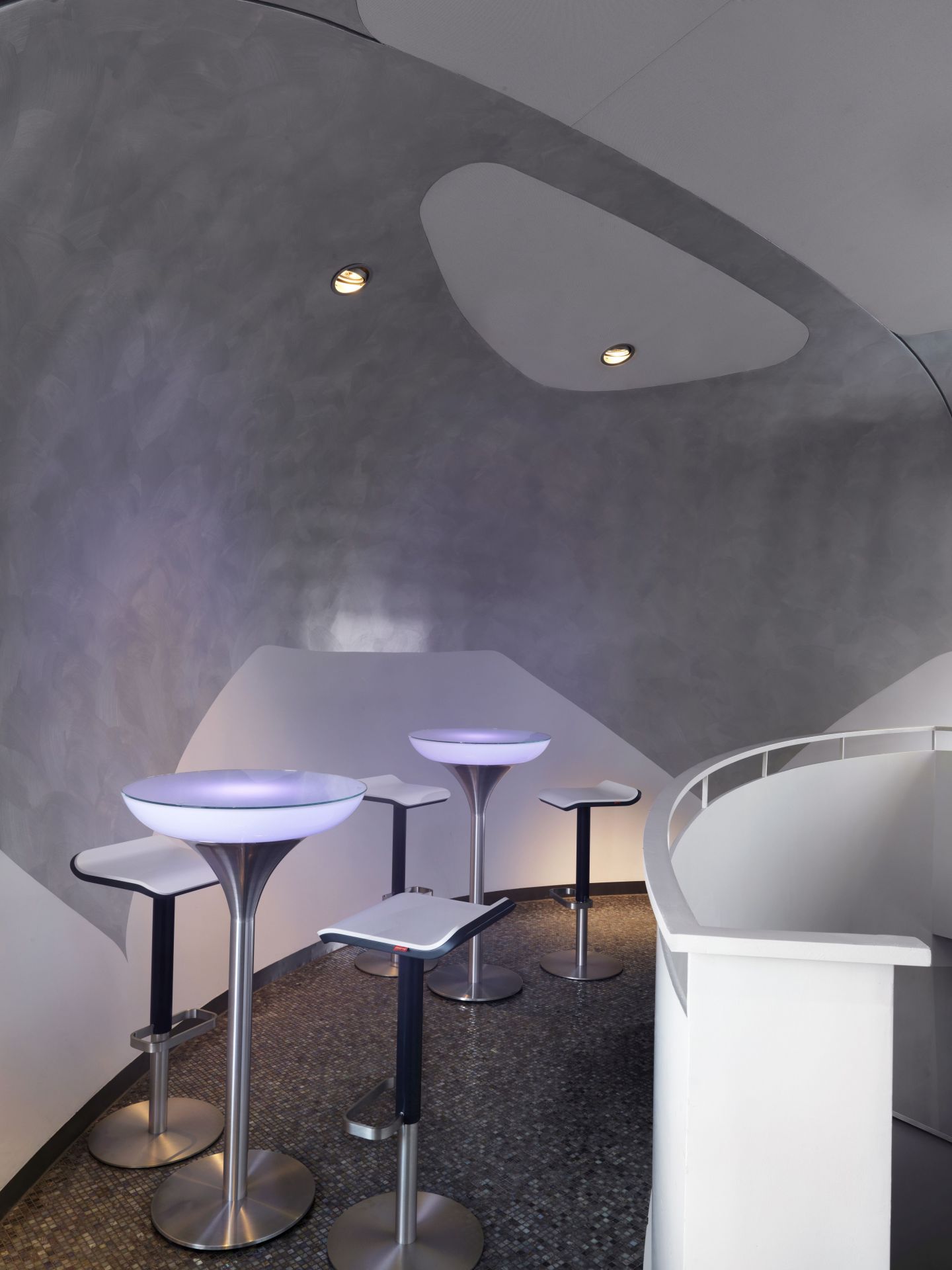 Mehrere höhenverstellbare ED Barhocker von Moree in modernem Ambiente mit Bar-Tischen und Beleuchtung.